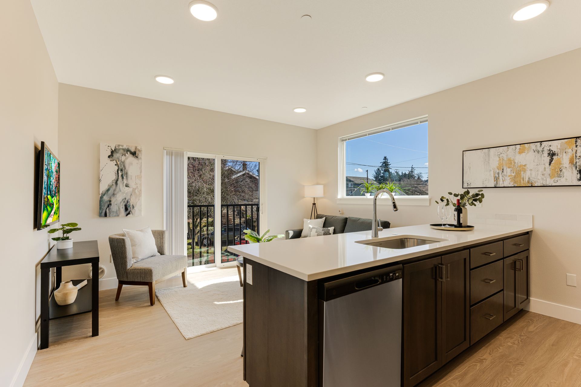 A kitchen with a sink , dishwasher , and stainless steel appliances in a living room.