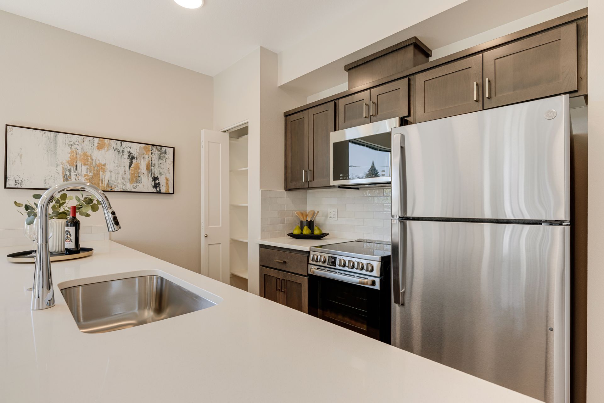 A kitchen with a sink , refrigerator , stove and microwave.