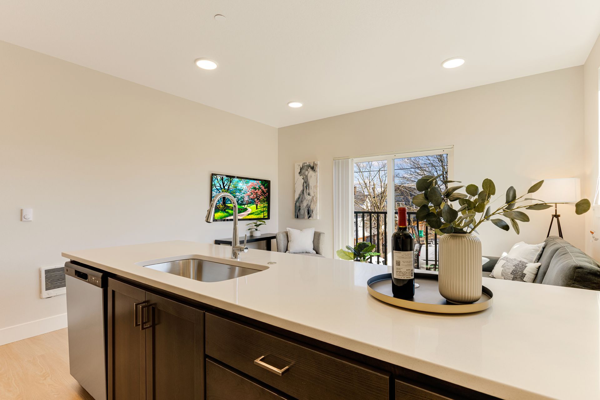A kitchen with a sink and a bottle of wine on the counter.