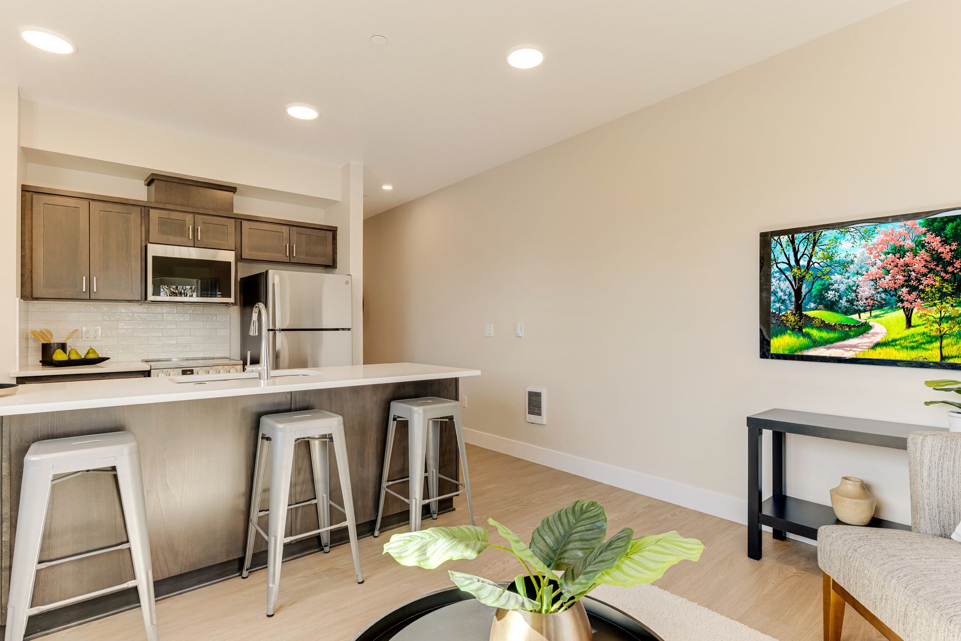 A living room with a kitchen and a flat screen tv.