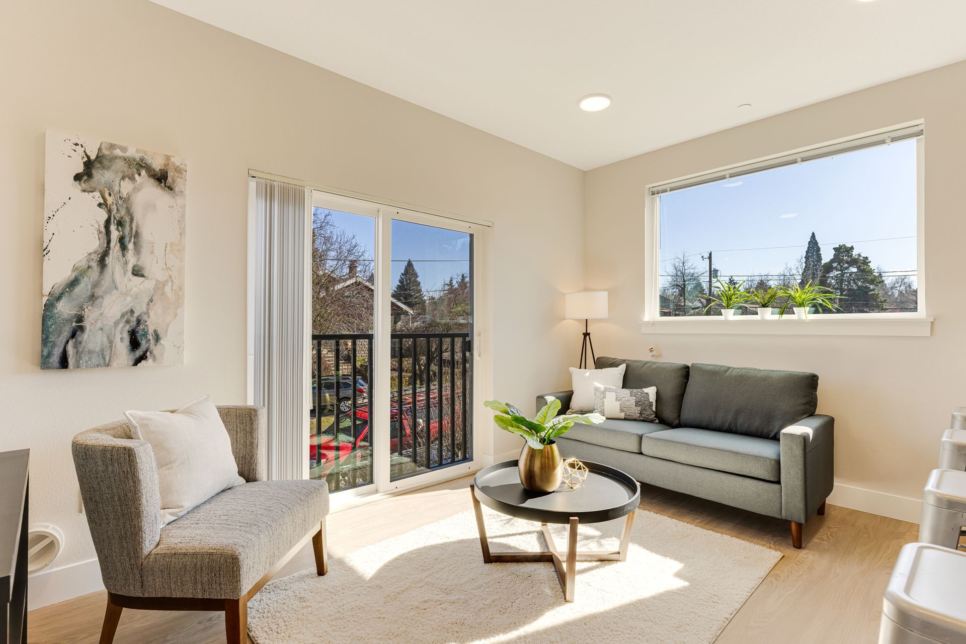 A living room with a couch , chair , coffee table and balcony.