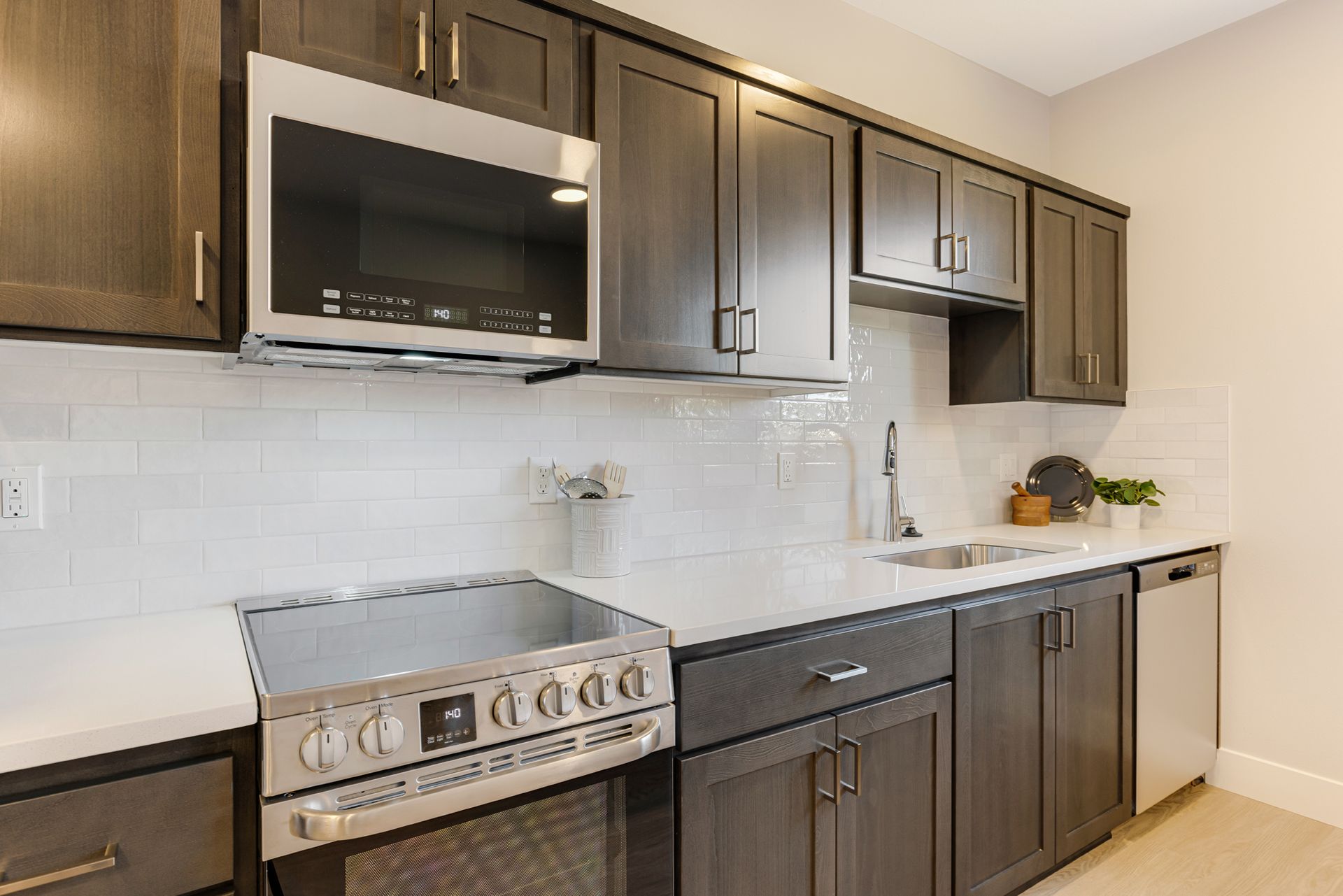 A kitchen with stainless steel appliances and gray cabinets.
