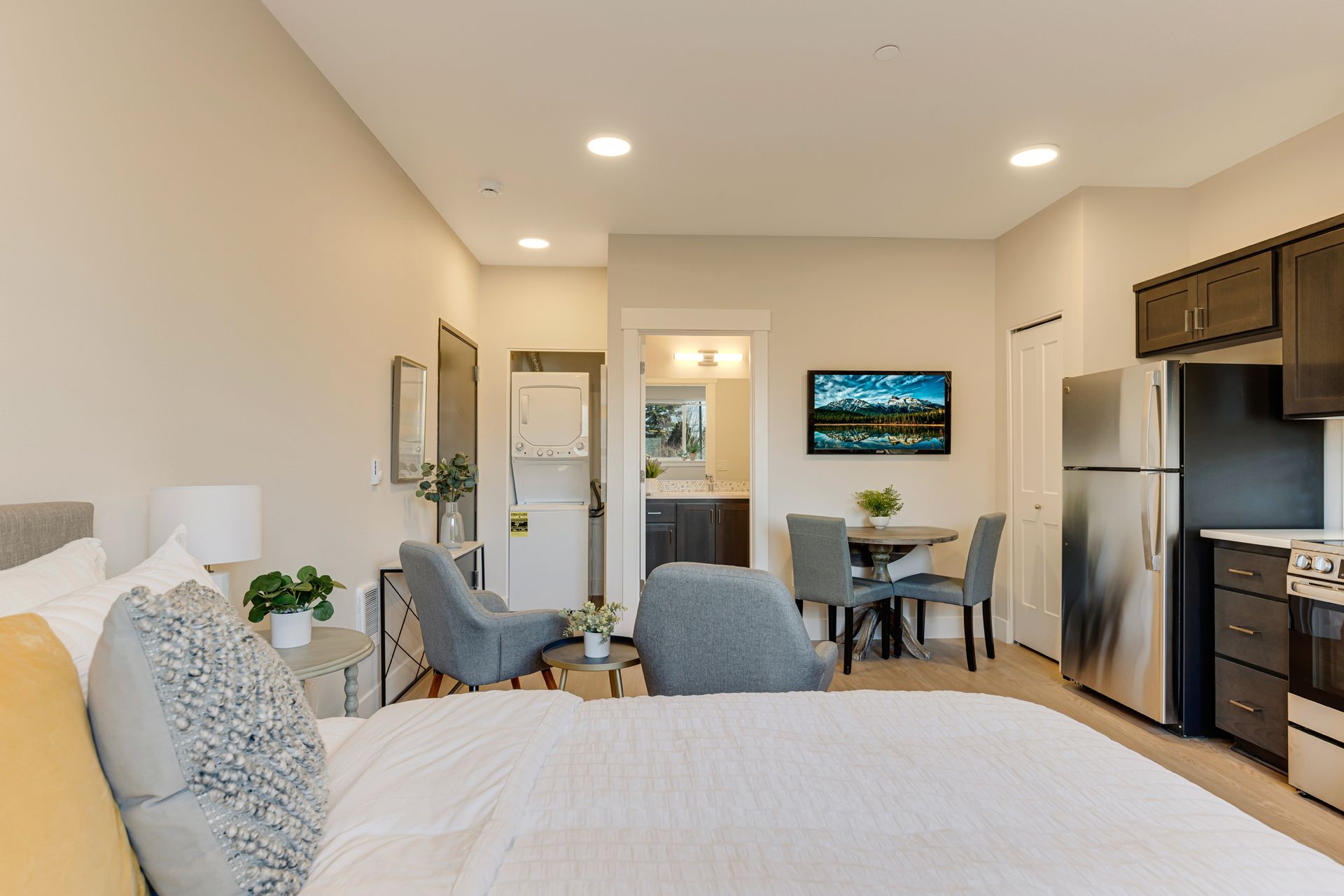A bedroom with a bed , chairs , a table and a refrigerator.