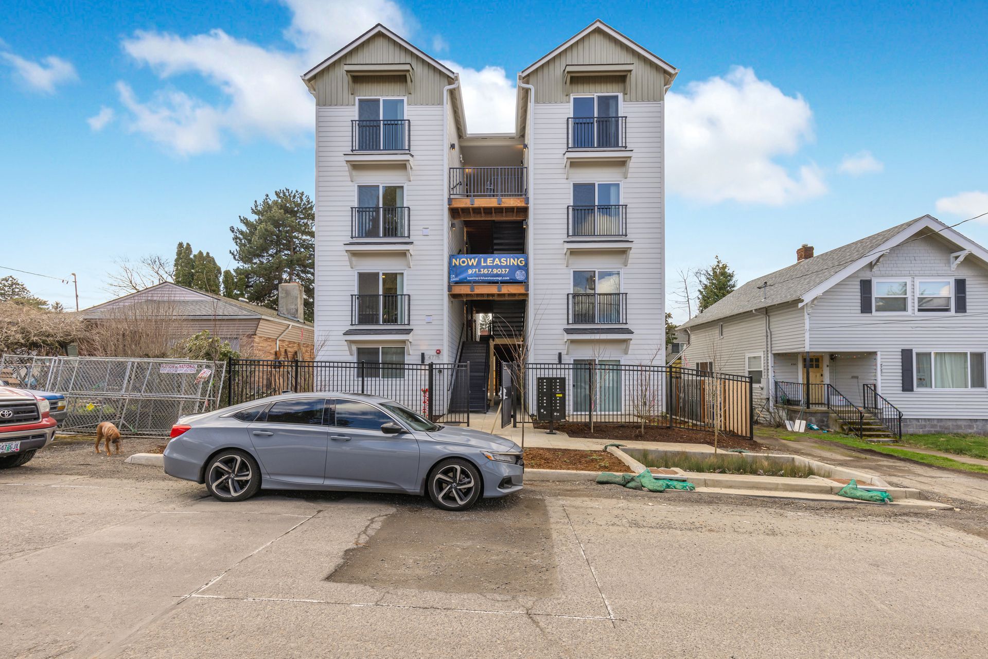 A gray car is parked in front of a building.