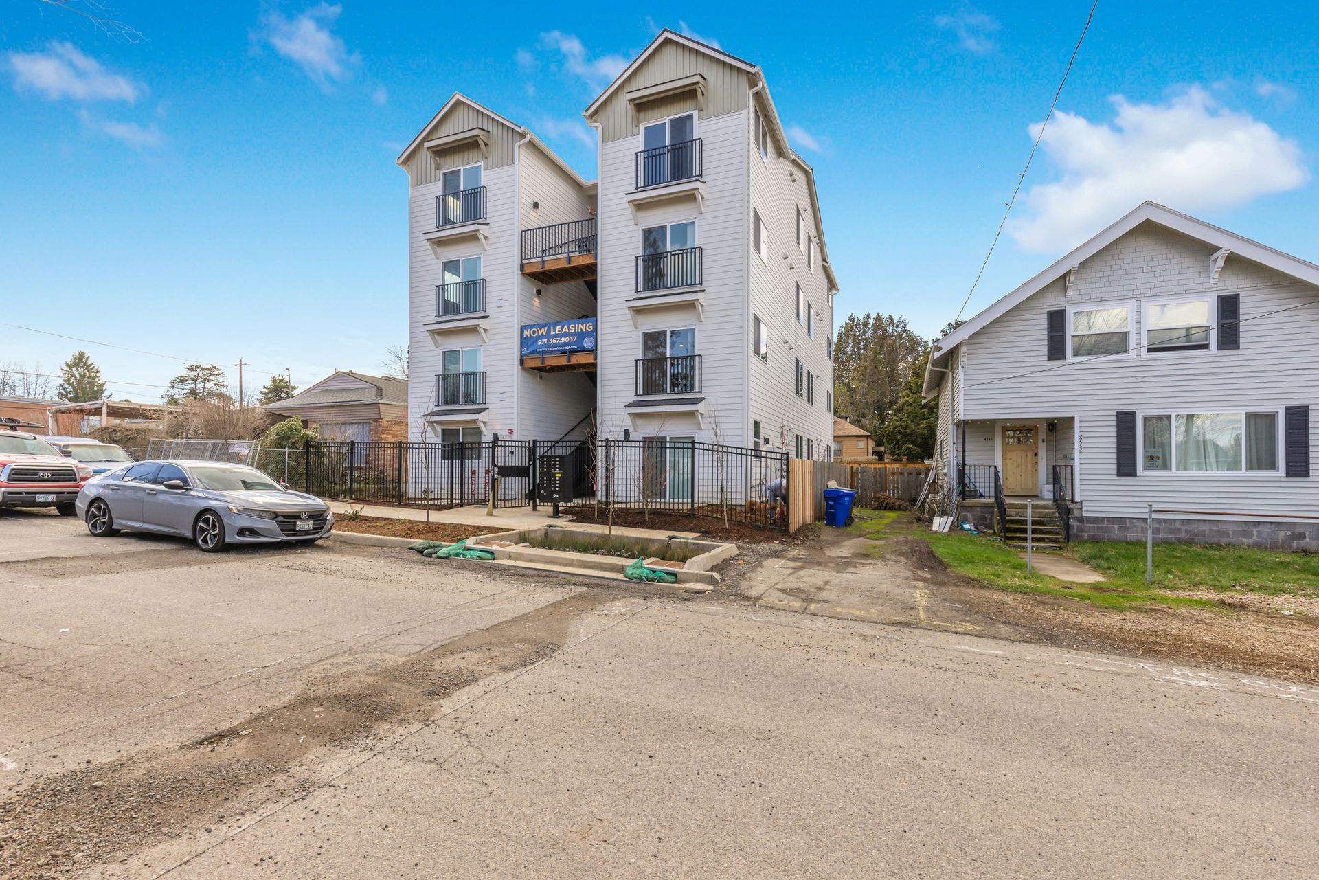 A car is parked in front of a building next to a house.