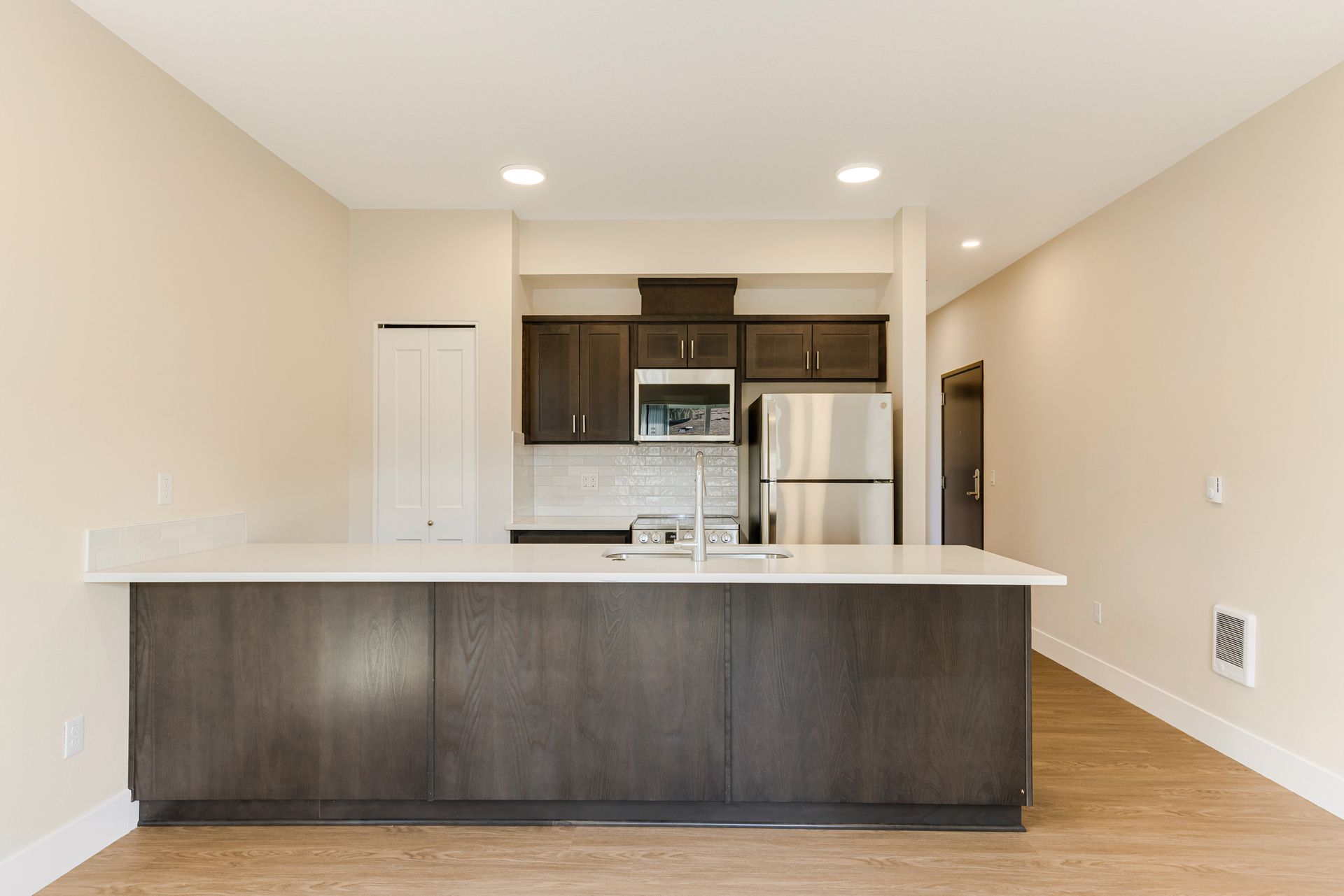 An empty kitchen with stainless steel appliances and a large island.