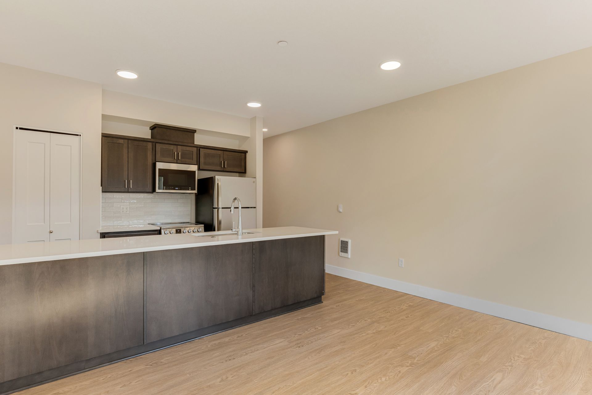 An empty kitchen with a large island in the middle of the room.