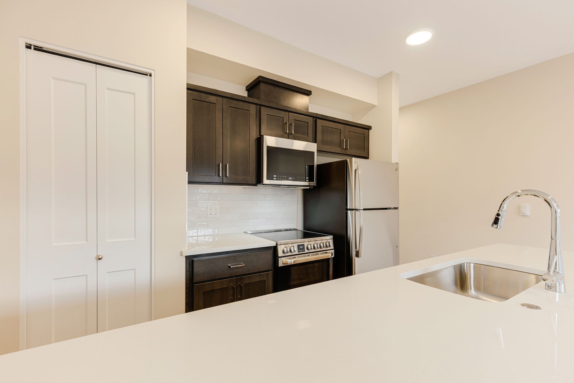 A kitchen with a sink , refrigerator , stove and microwave.