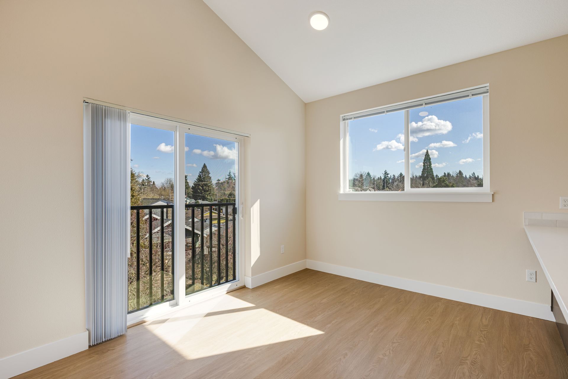An empty room with a balcony and sliding glass doors.