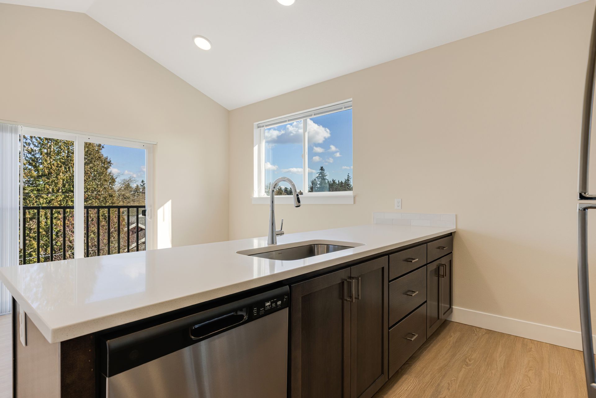 A kitchen with a sink , dishwasher , refrigerator and window.