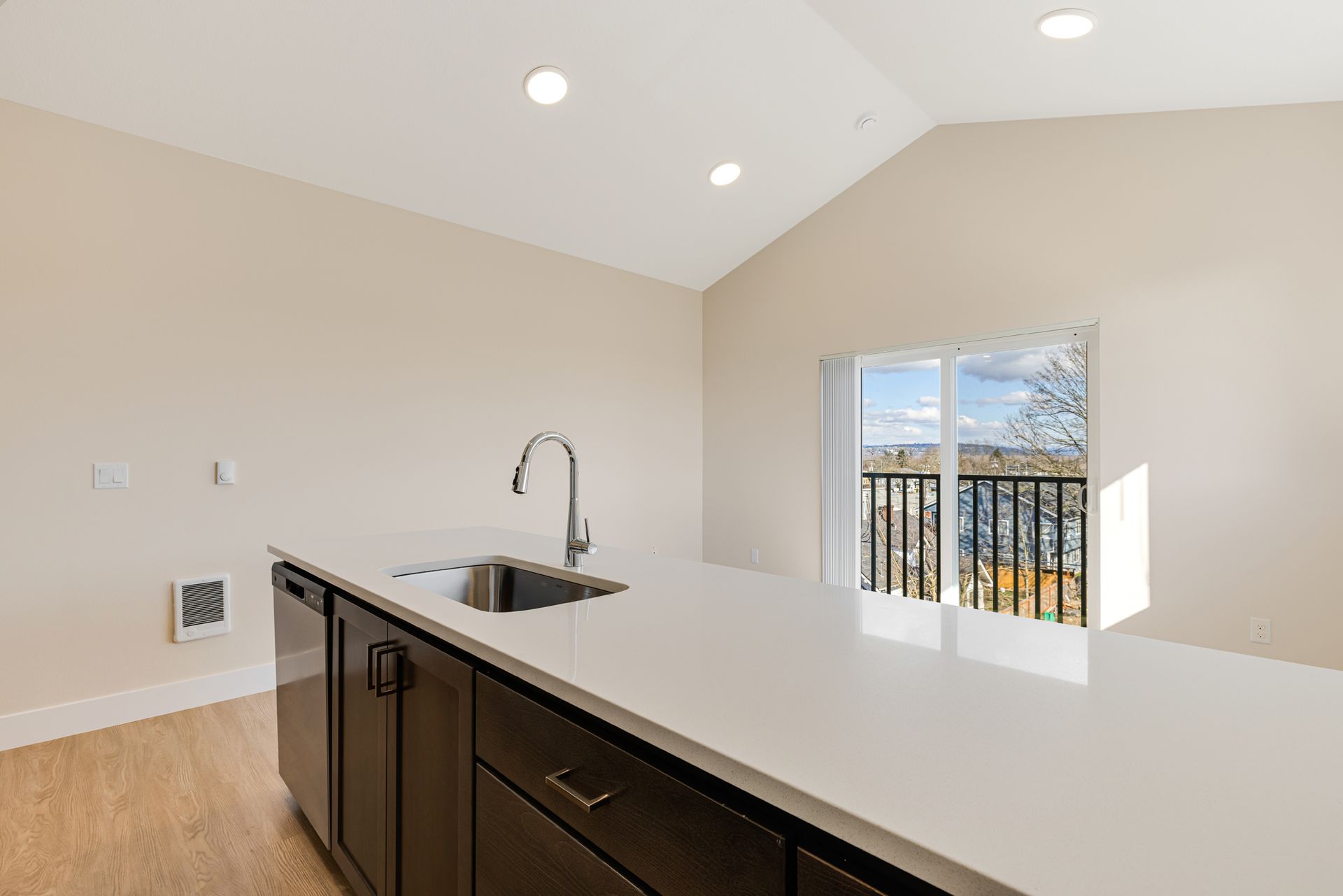 A kitchen with a sink , dishwasher , and sliding glass door.