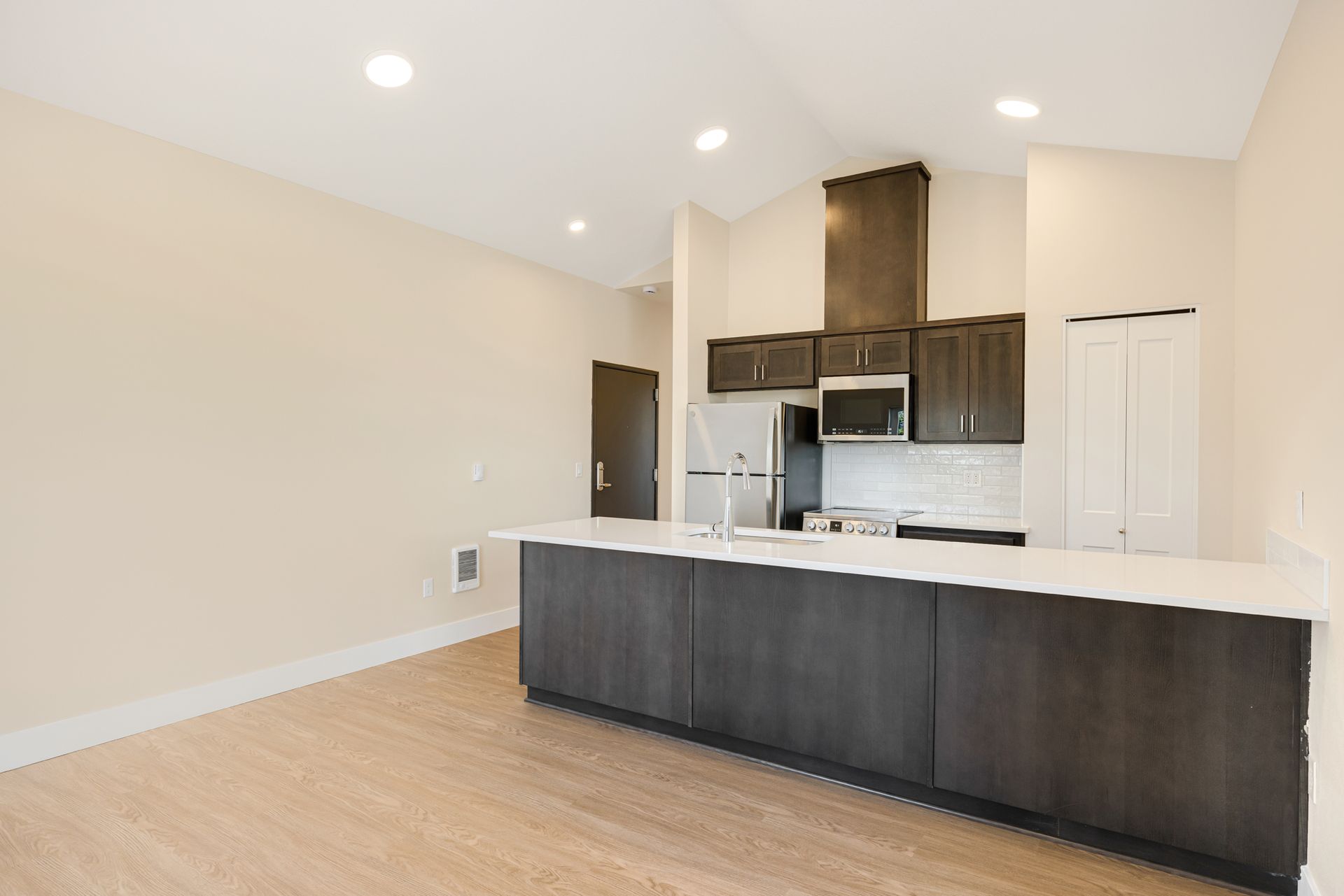 An empty kitchen with a large island and stainless steel appliances