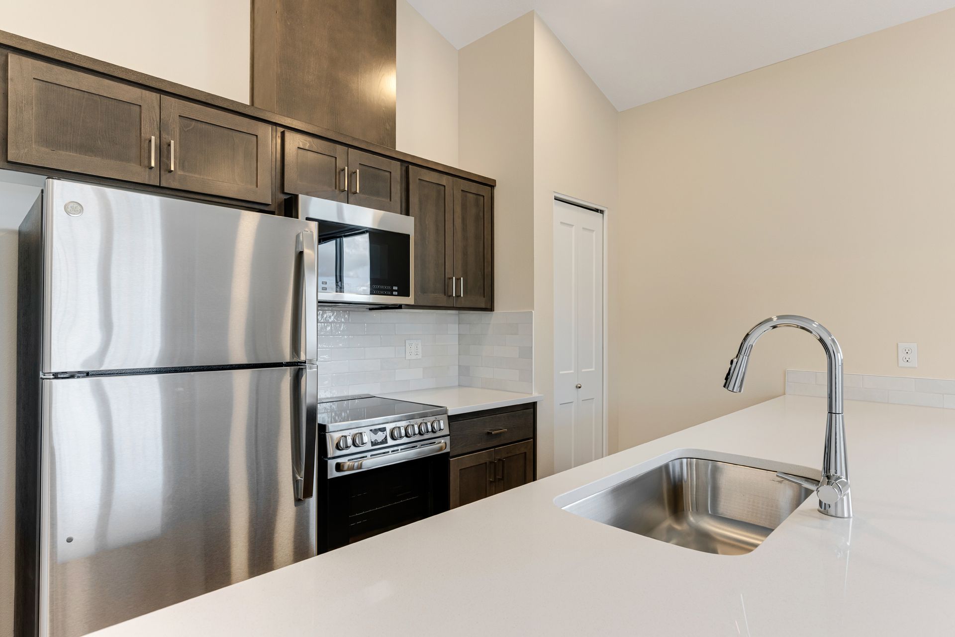 A kitchen with a stainless steel refrigerator , stove , microwave and sink.