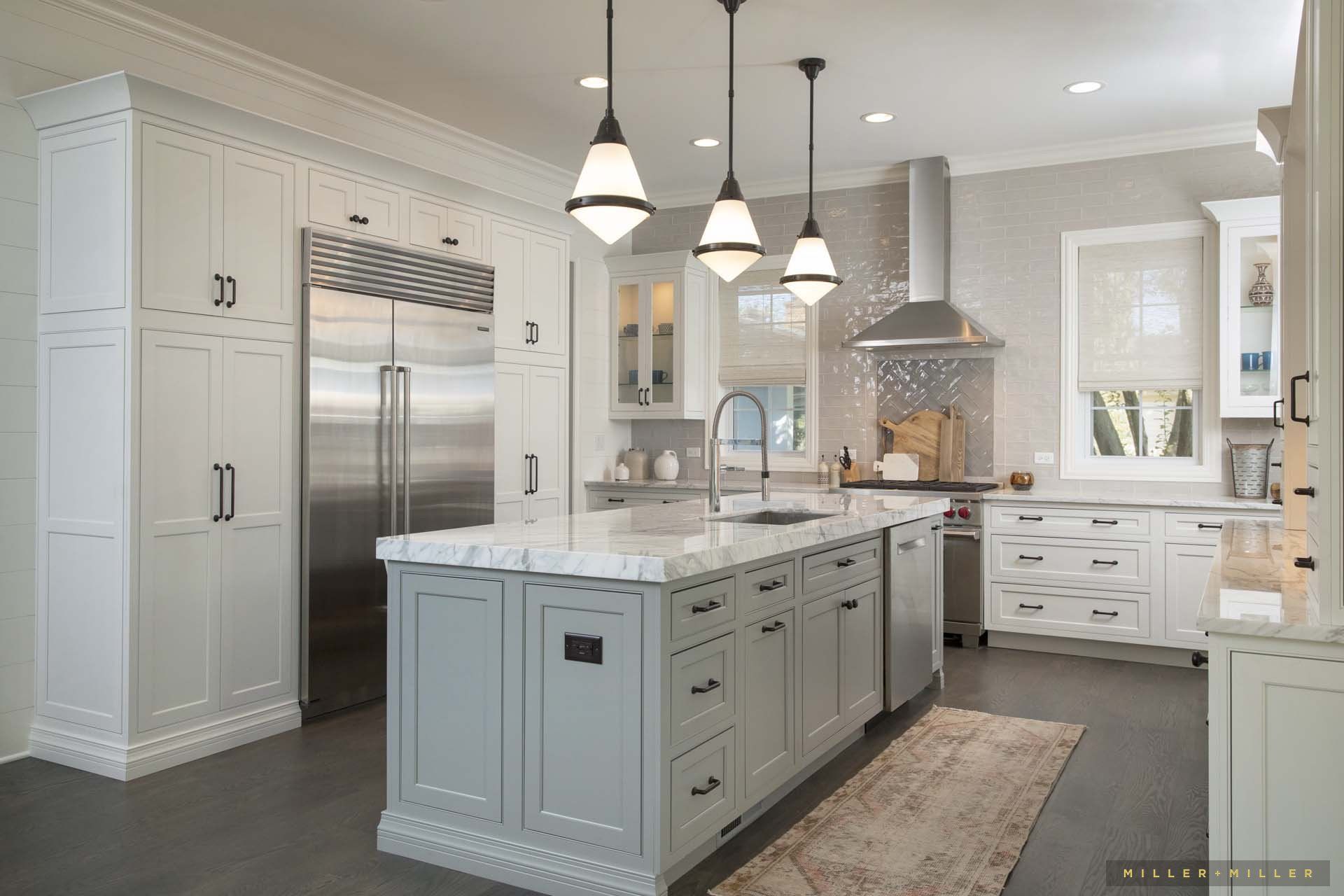 A kitchen with white cabinets , stainless steel appliances , and a large island.