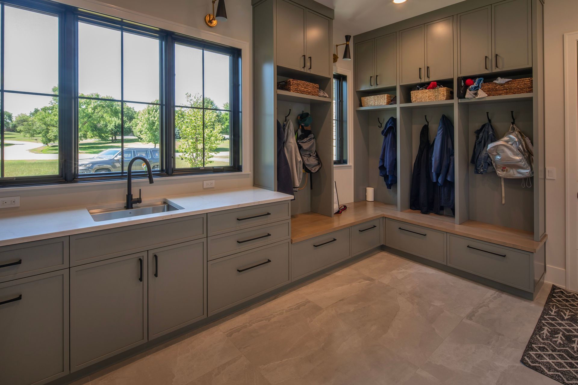 A laundry room with lots of cabinets and drawers and a sink.