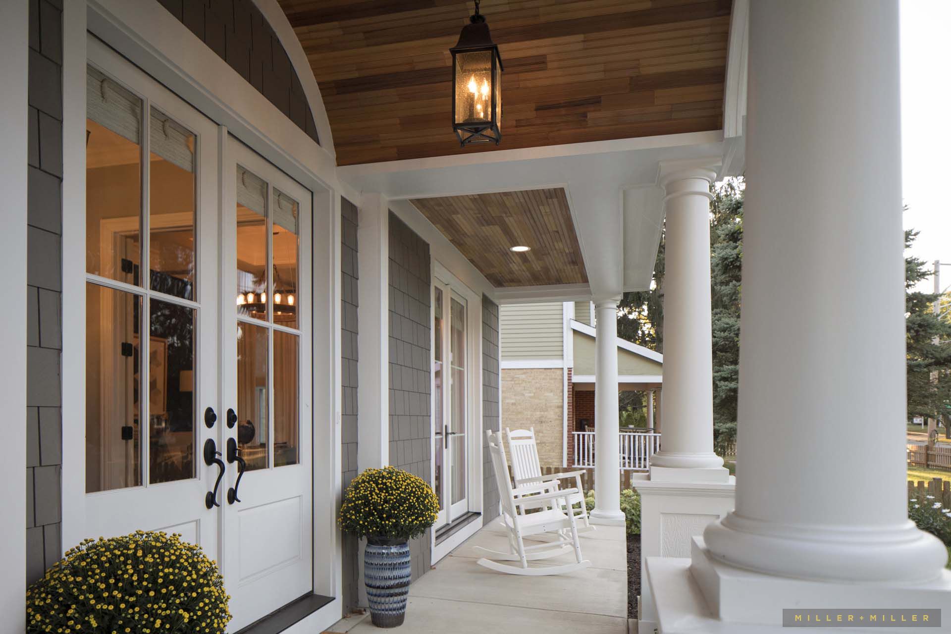 A porch with rocking chairs and a lantern hanging from the ceiling