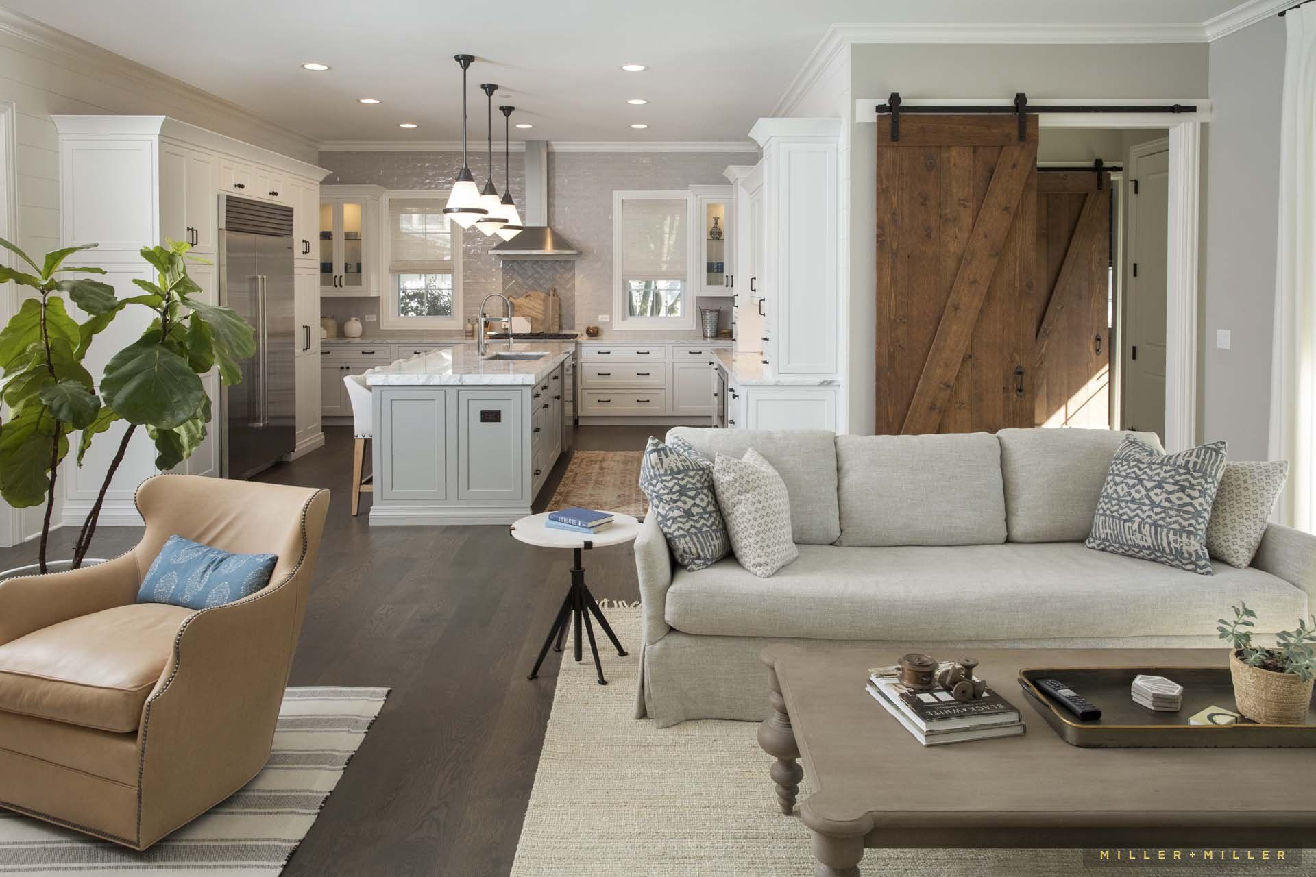 A living room with a couch , chair , coffee table and sliding barn door.
