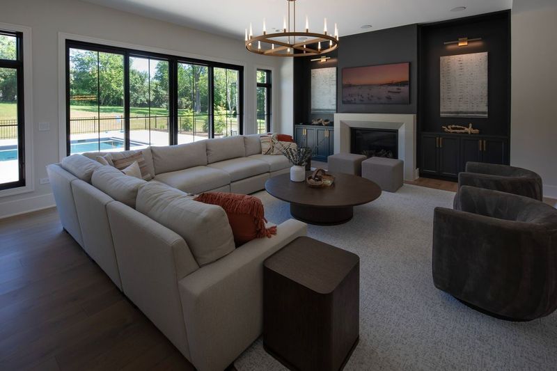 A living room with a large sectional couch , two chairs , a coffee table and a fireplace.