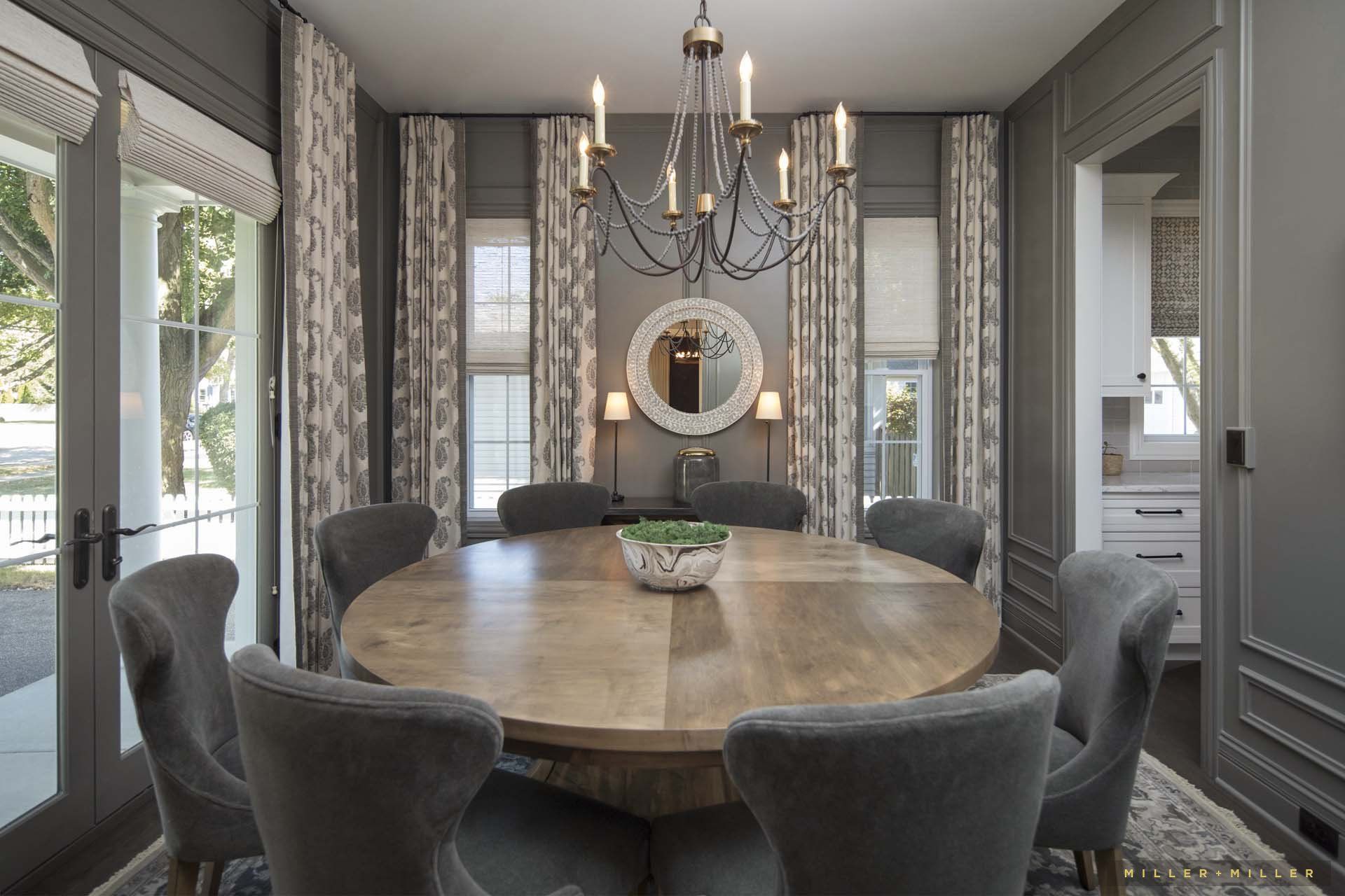 A dining room with a round table and chairs and a chandelier