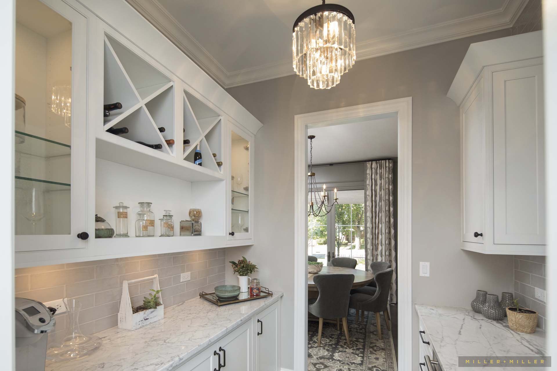 A kitchen with white cabinets and a wine rack and a chandelier hanging from the ceiling.