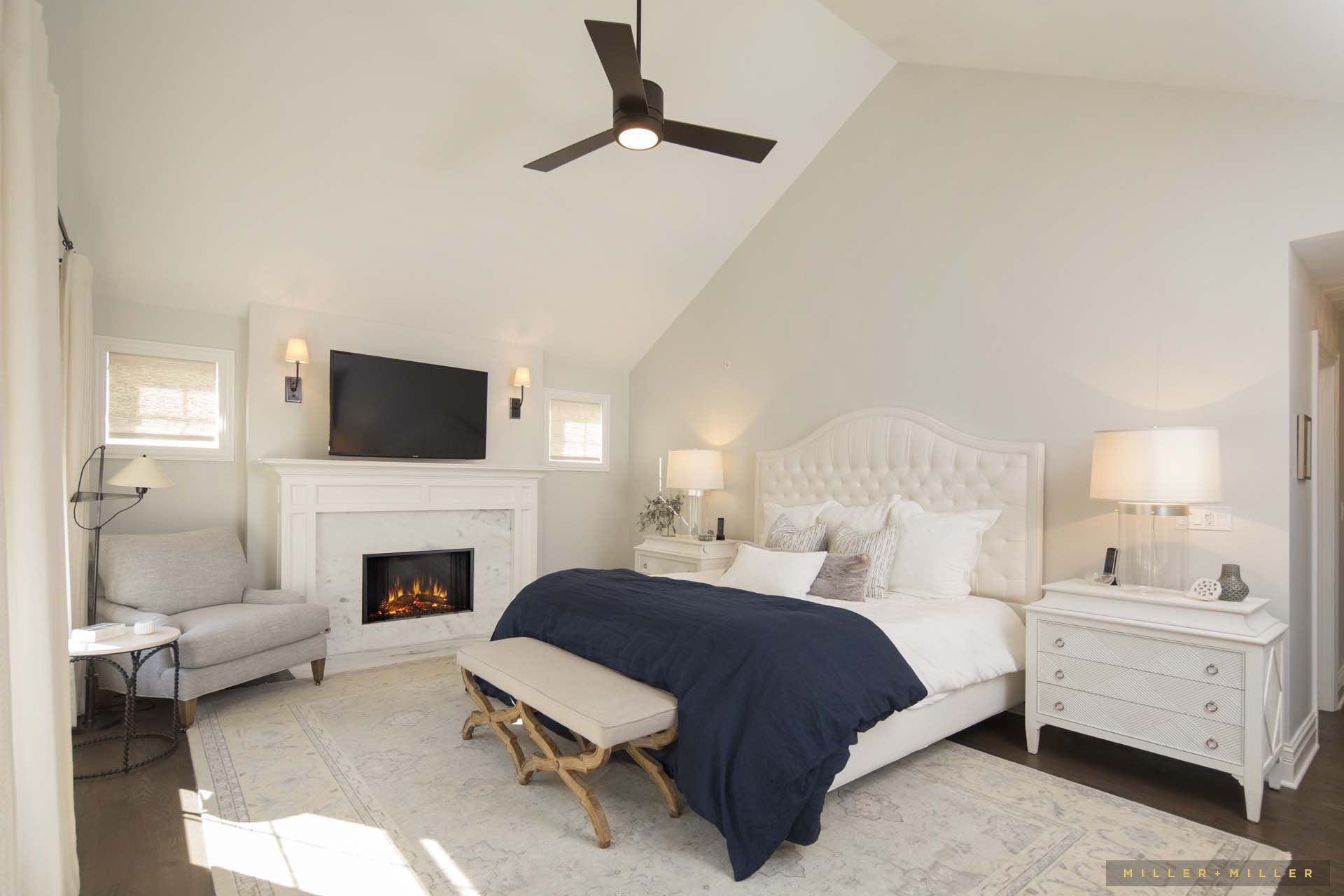 A bedroom with a bed , fireplace , television and ceiling fan.