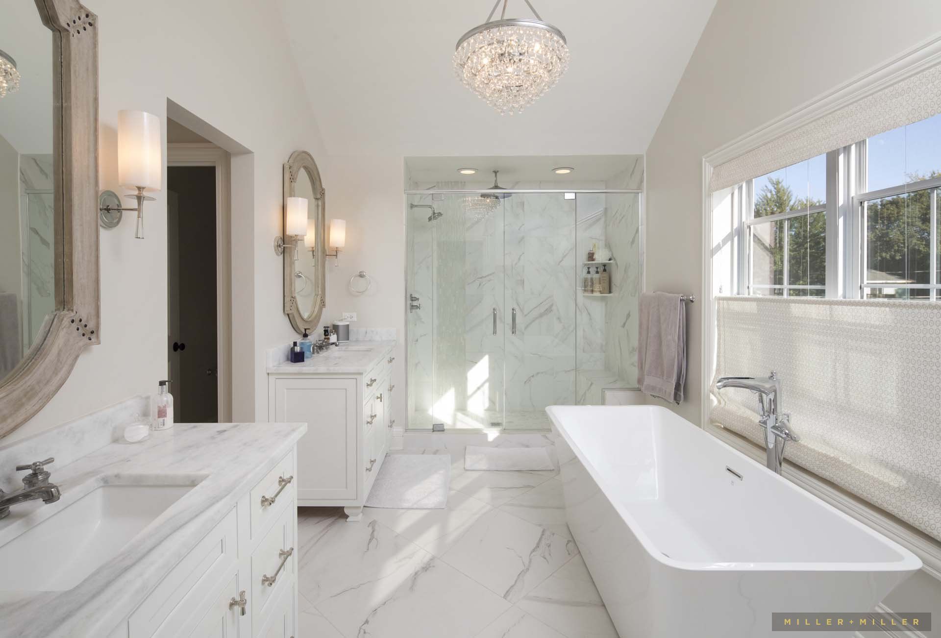 A bathroom with a tub , sink , mirror and shower.