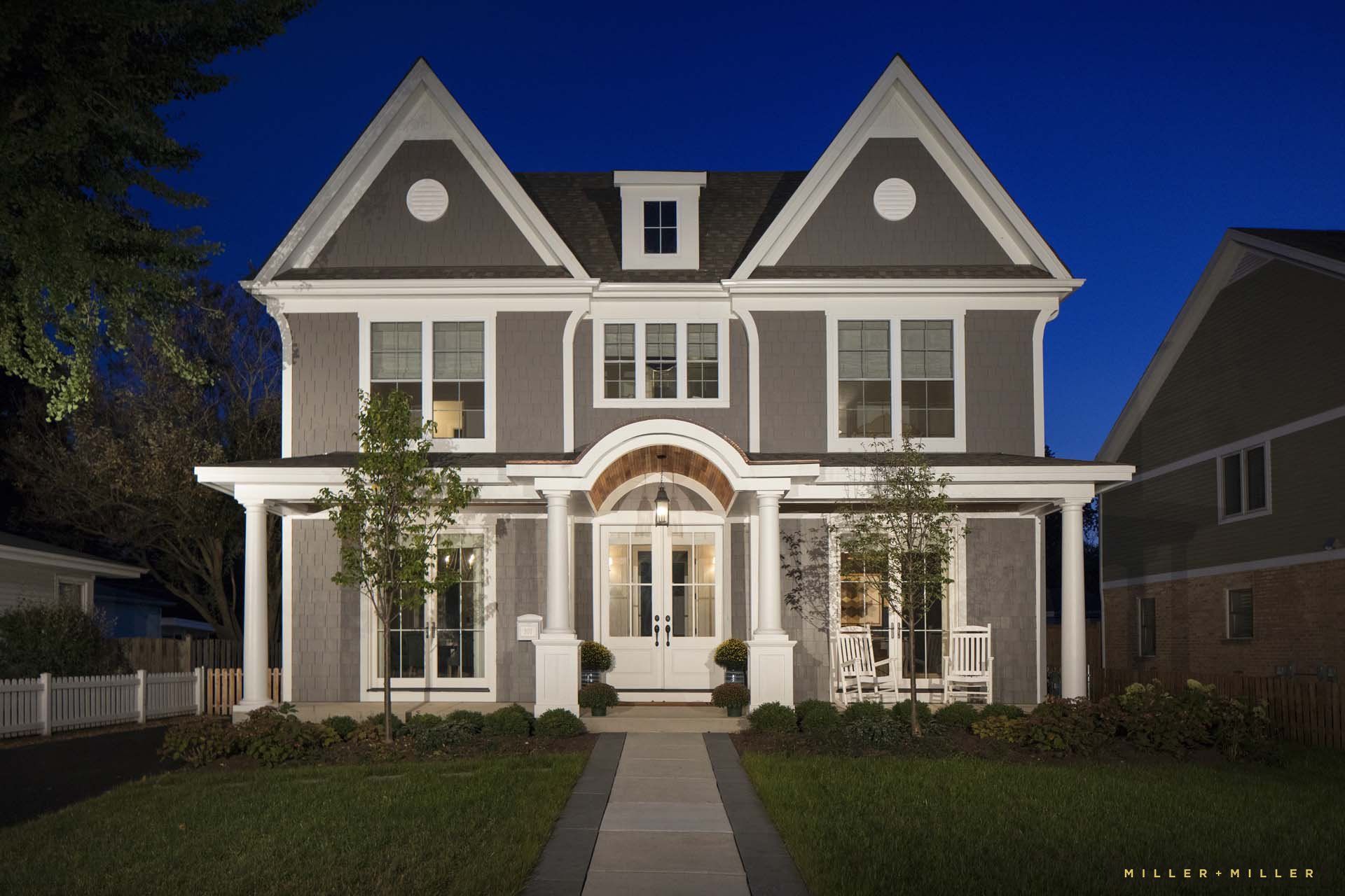 A large house with a porch is lit up at night