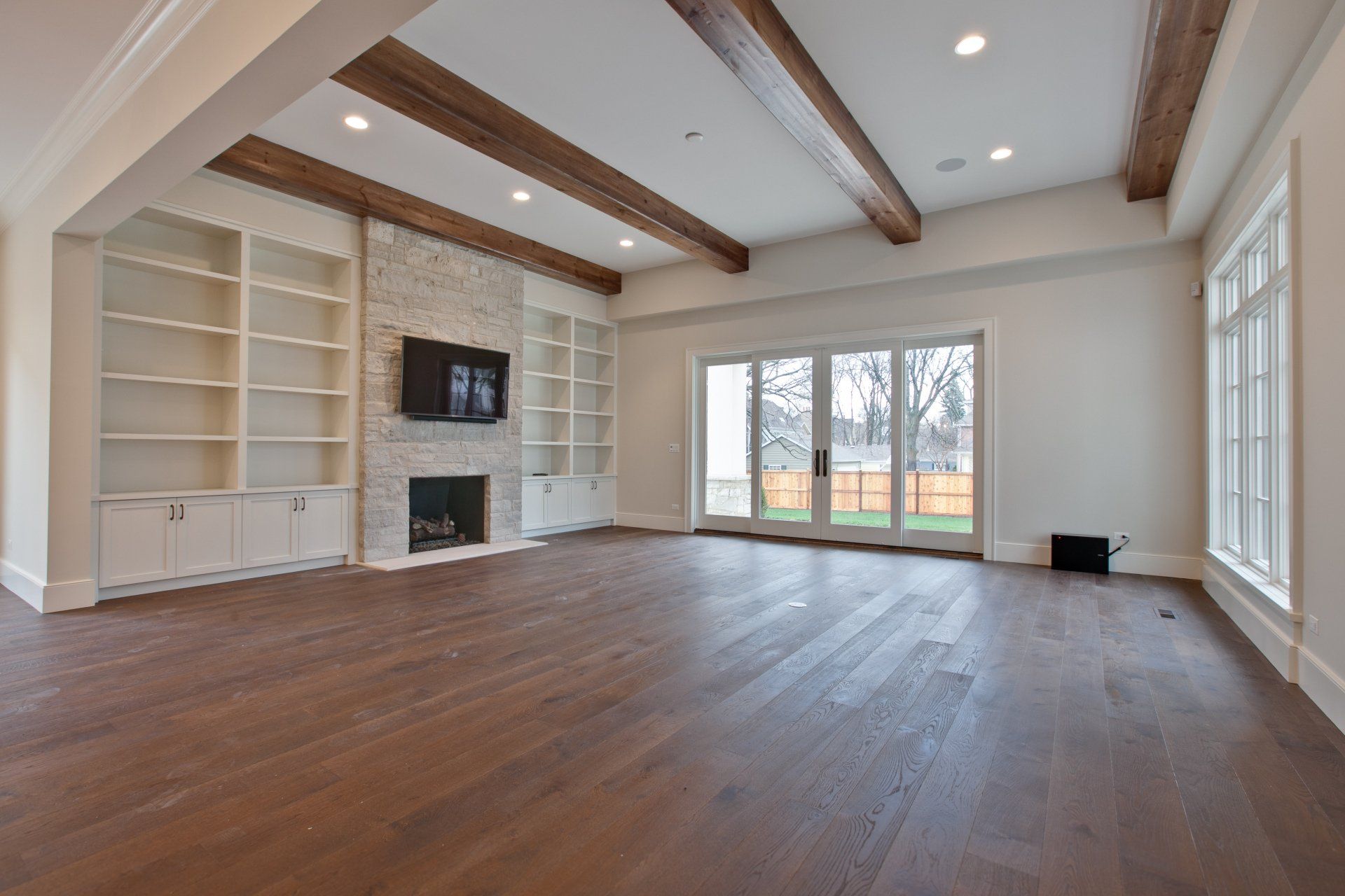 An empty living room with hardwood floors and a fireplace.