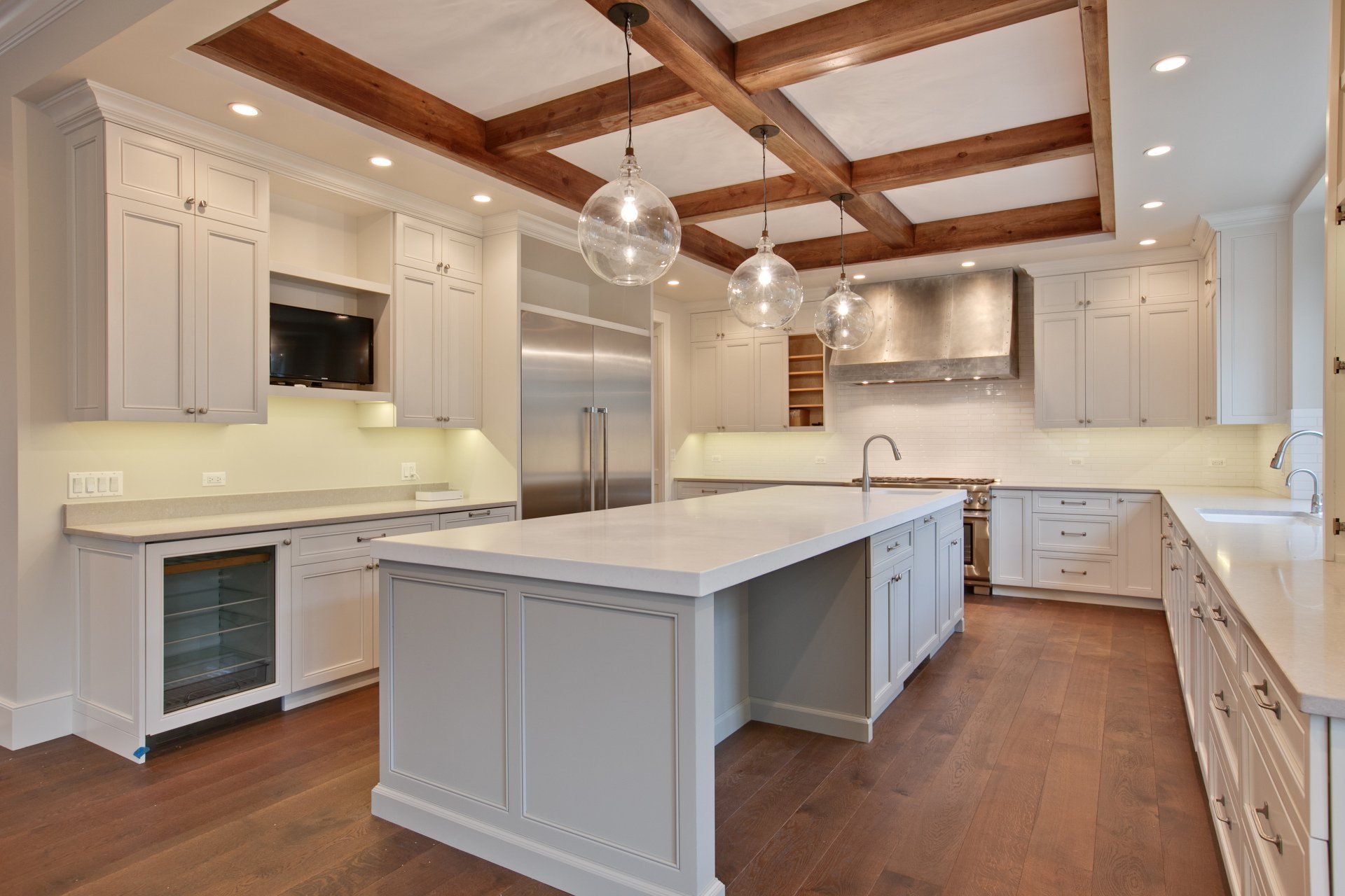 A kitchen with white cabinets and stainless steel appliances and a large island in the middle.