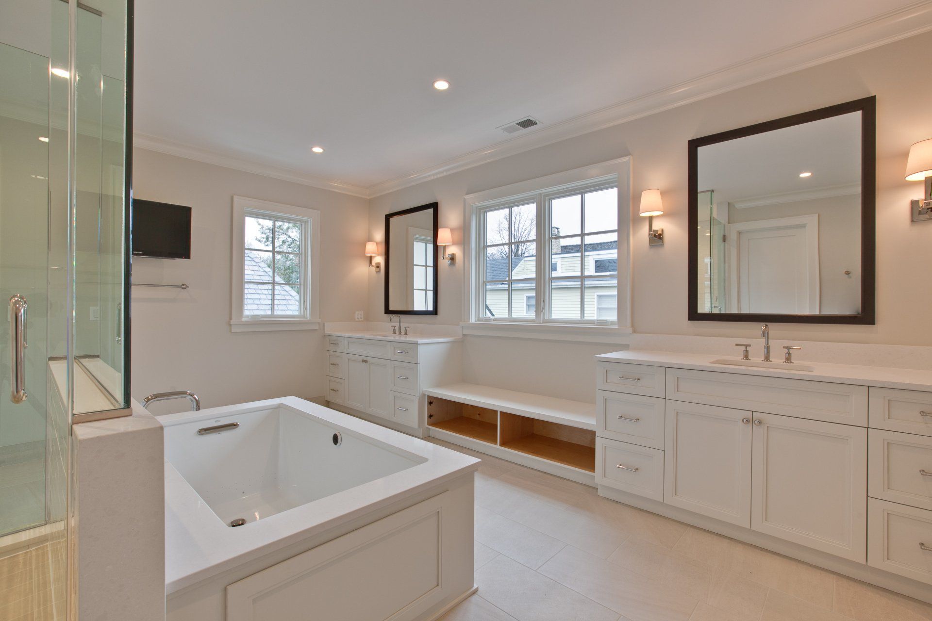 A bathroom with a bathtub , sinks , mirrors and a walk in shower.