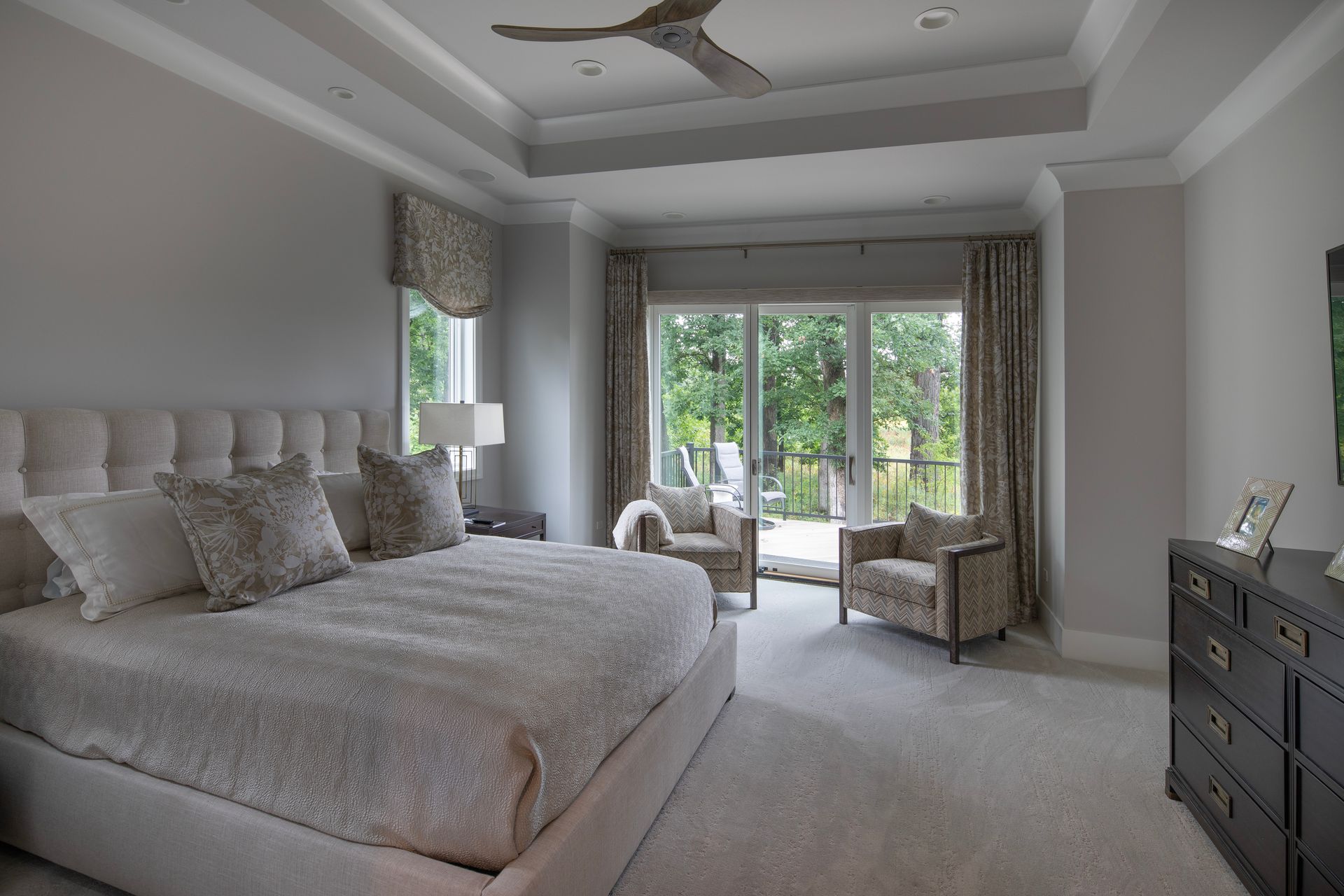 A bedroom with a large bed , chairs and a ceiling fan.
