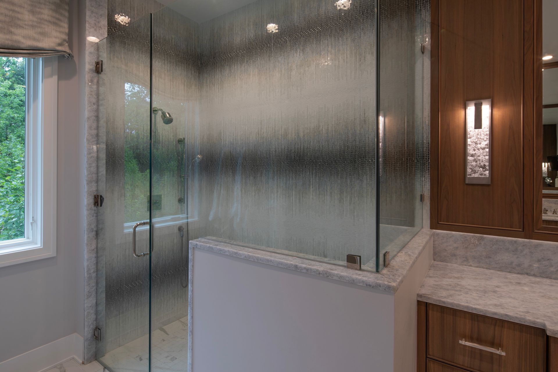 A bathroom with a walk in shower and a sink.