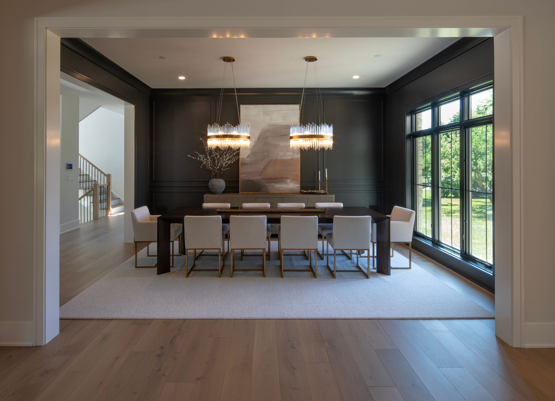 A dining room with a long table and chairs and a large window.