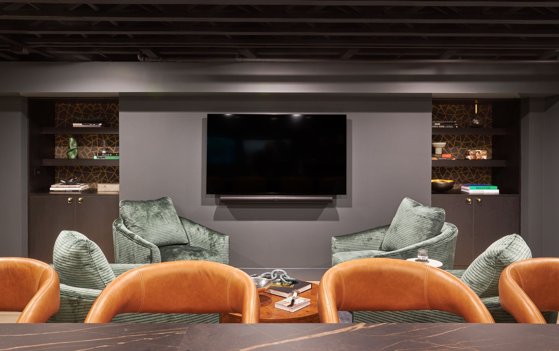 A living room with a table and chairs and a flat screen tv on the wall.