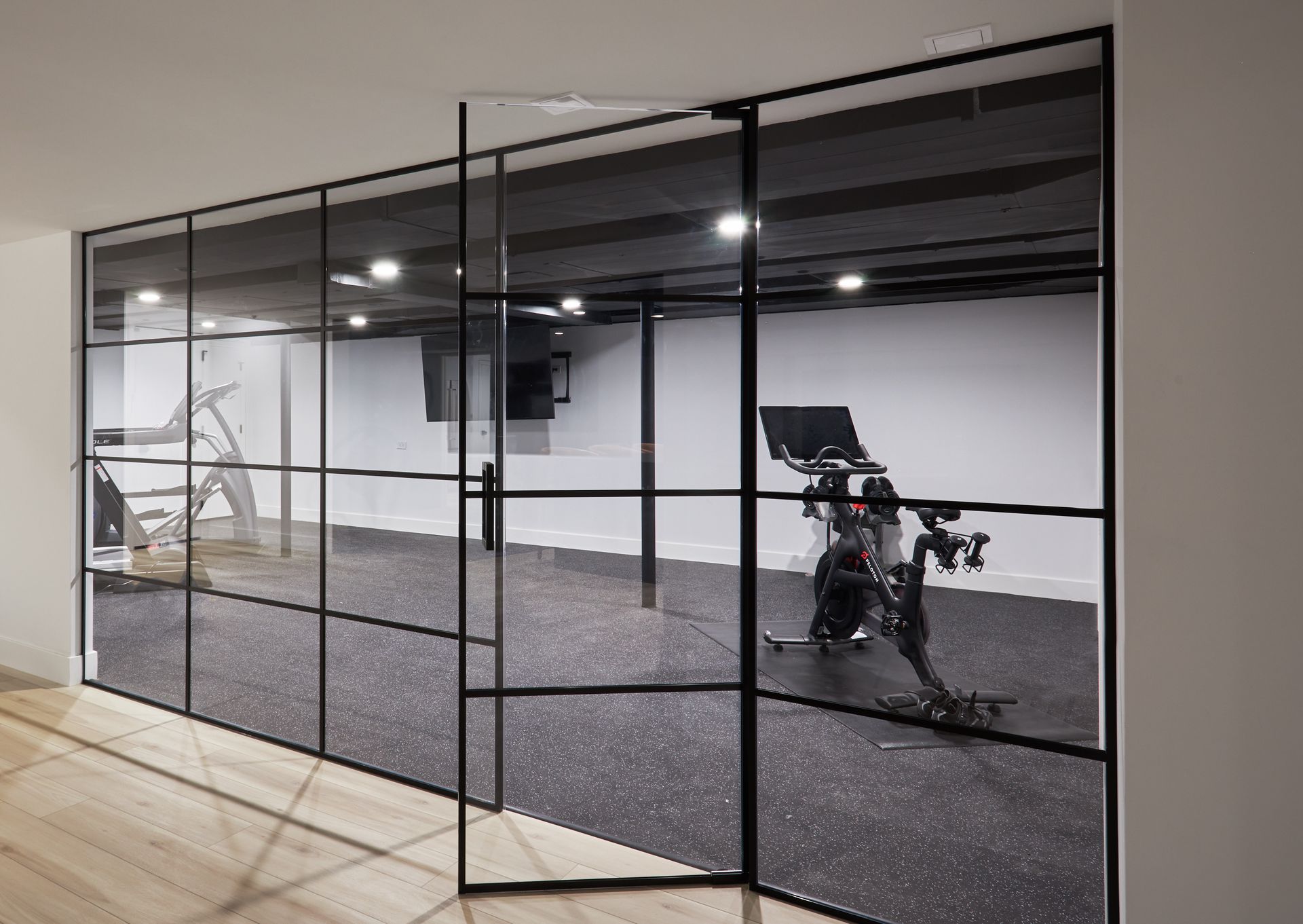 A bicycle is parked in a gym behind a glass wall.