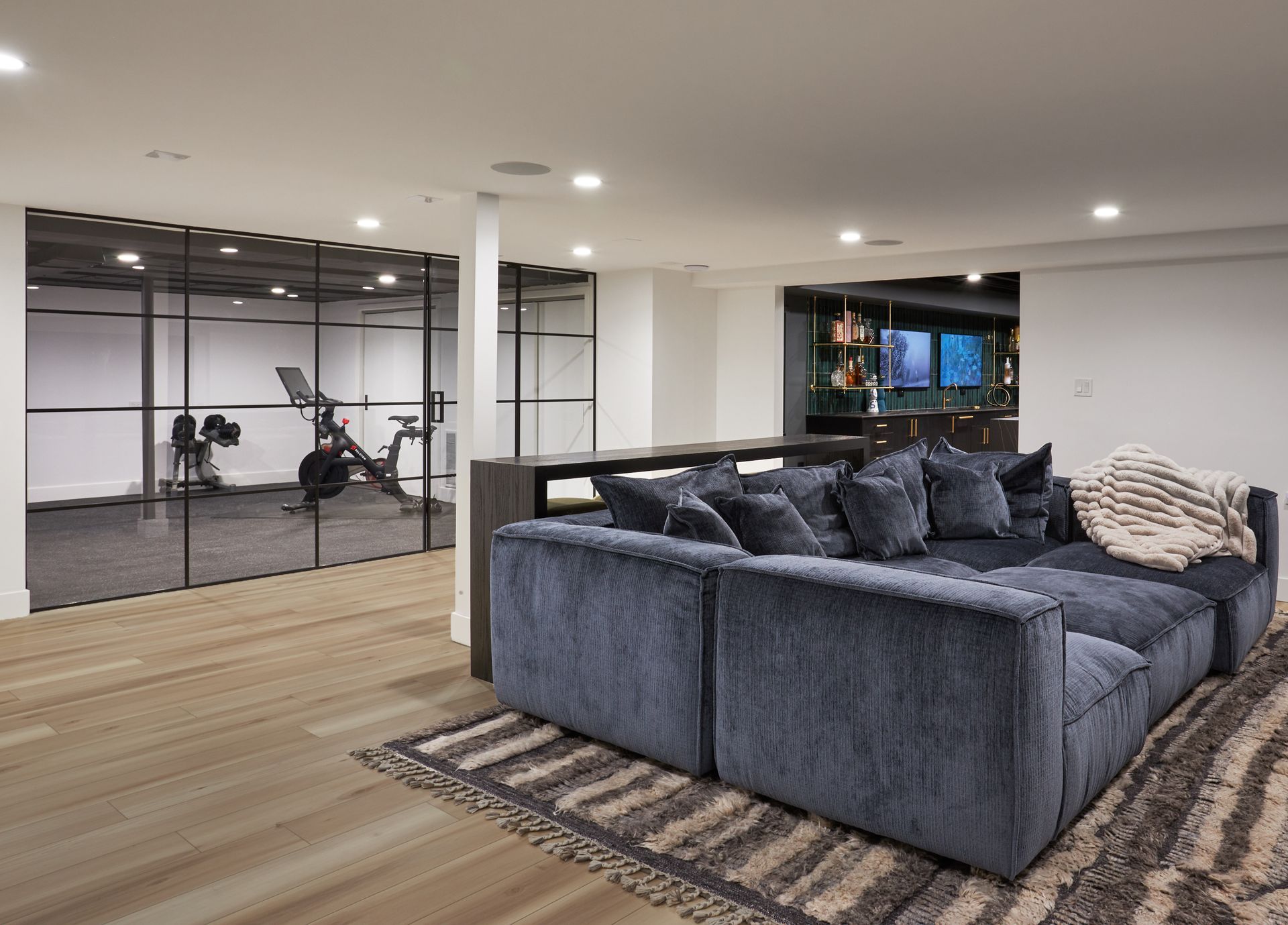 A living room with a large couch and a gym in the background.