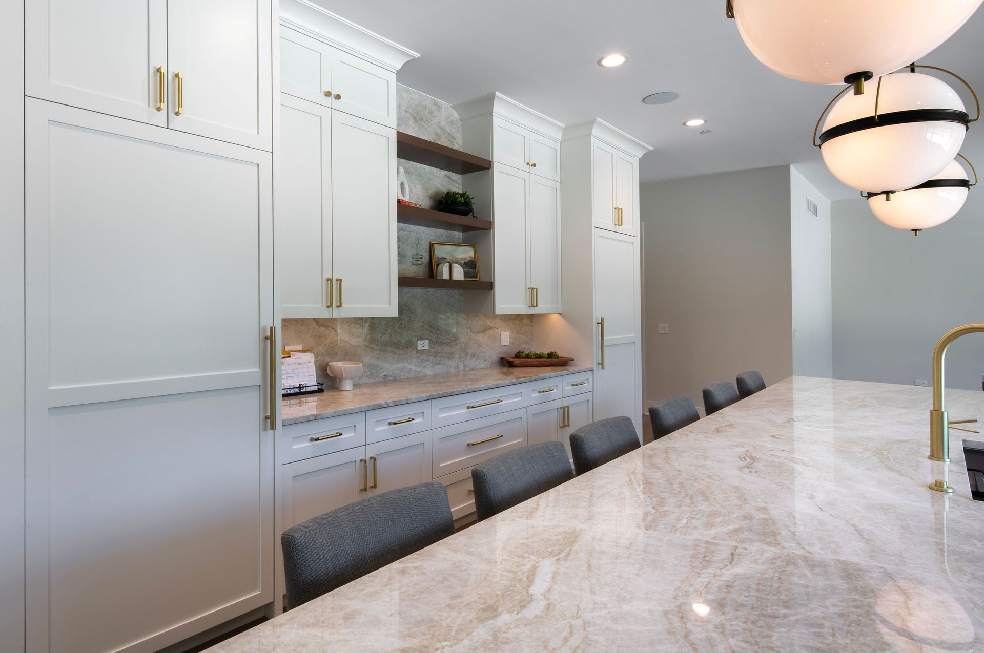 A kitchen with white cabinets and marble counter tops.