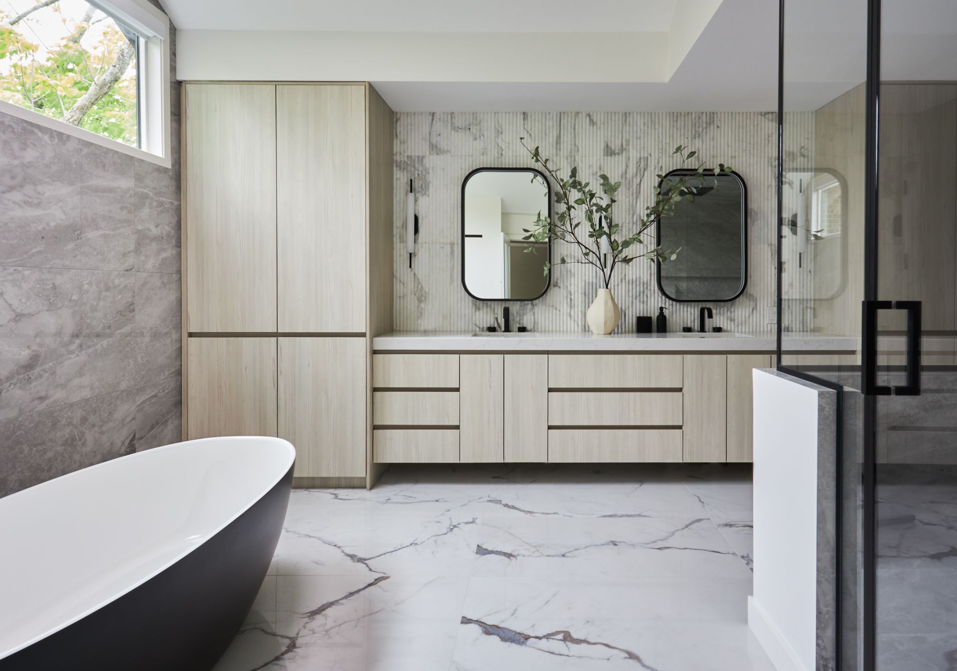 A bathroom with a bathtub , sink , mirror and cabinets.