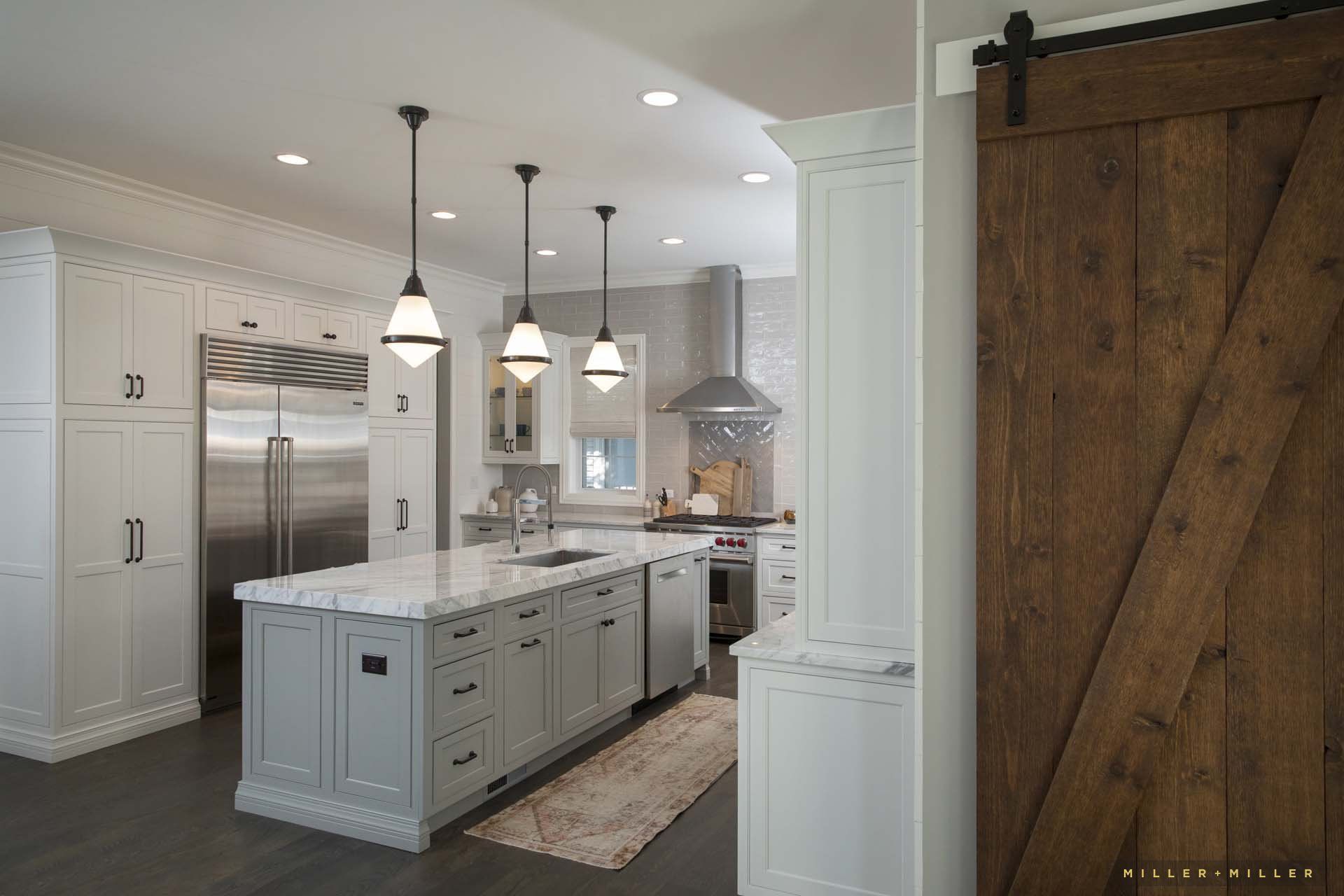 A kitchen with white cabinets and stainless steel appliances and a sliding barn door.