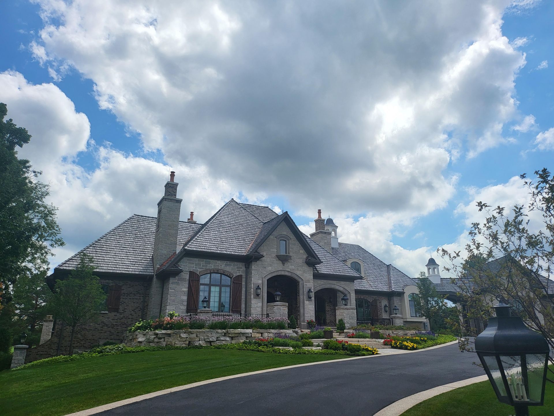 A large house is sitting on top of a lush green hillside.