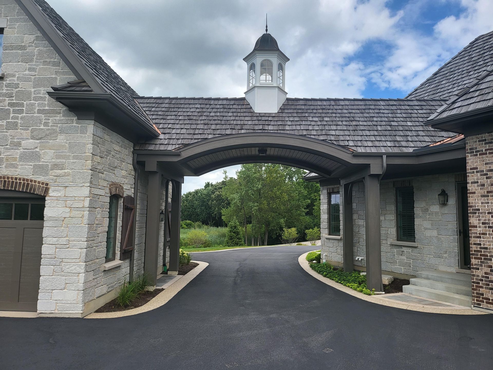 A driveway leading to a house with a roof that has shingles on it