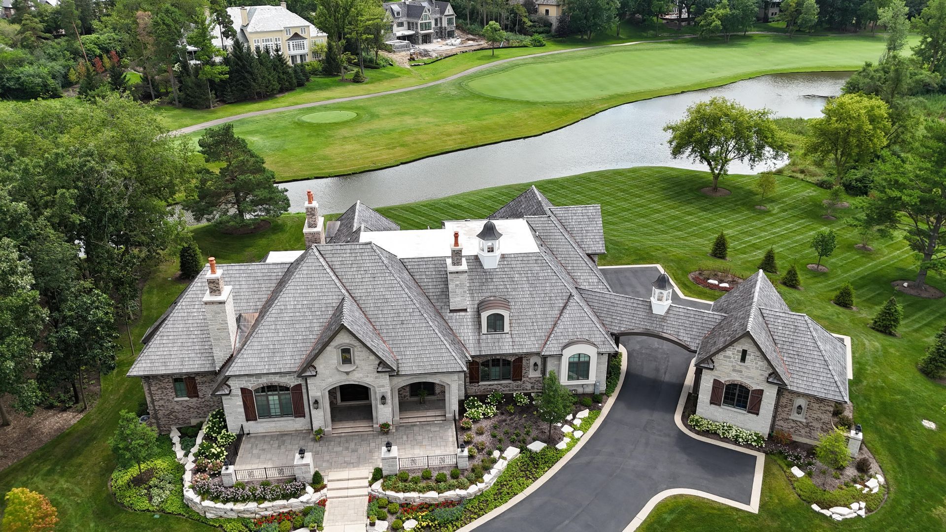 An aerial view of a large house with a golf course in the background.