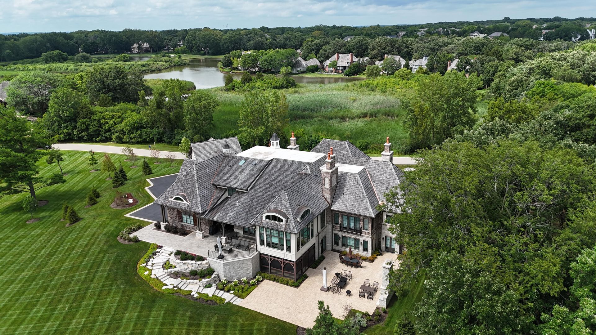 An aerial view of a large house surrounded by trees and grass.