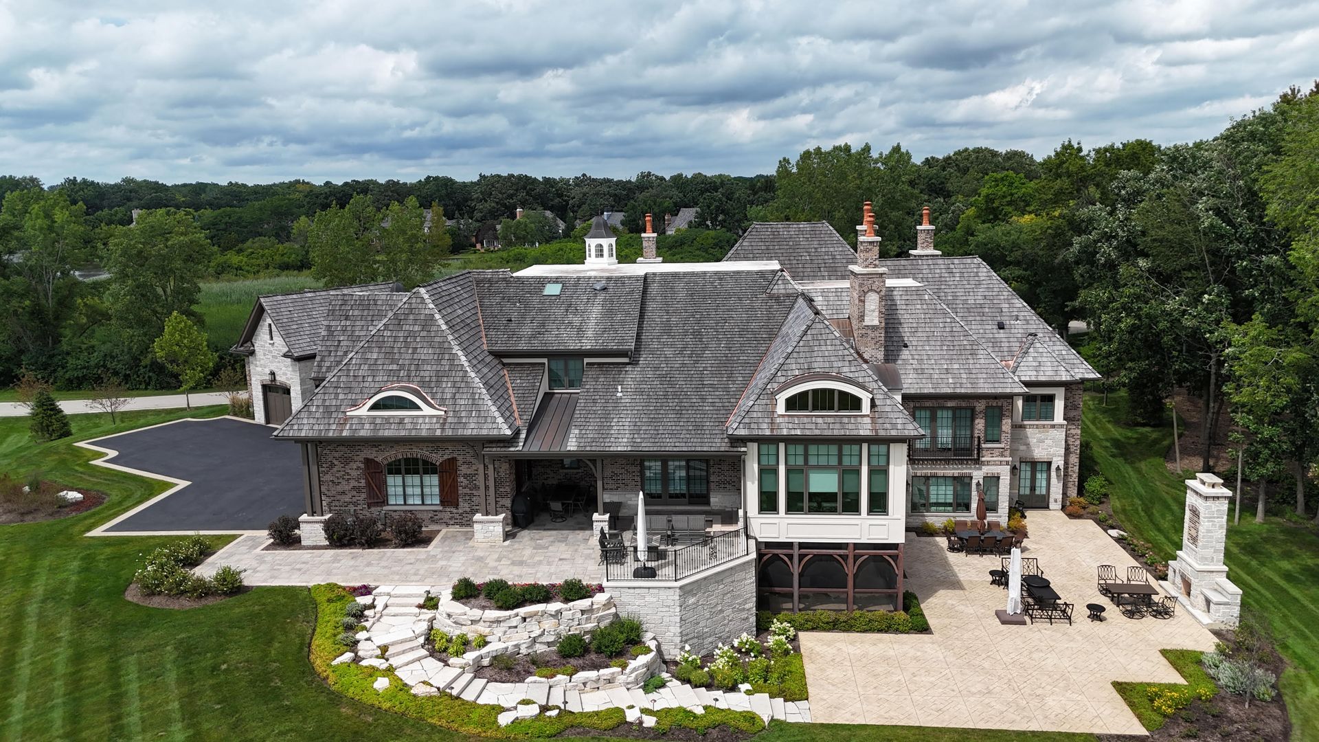 An aerial view of a large house surrounded by trees and grass.