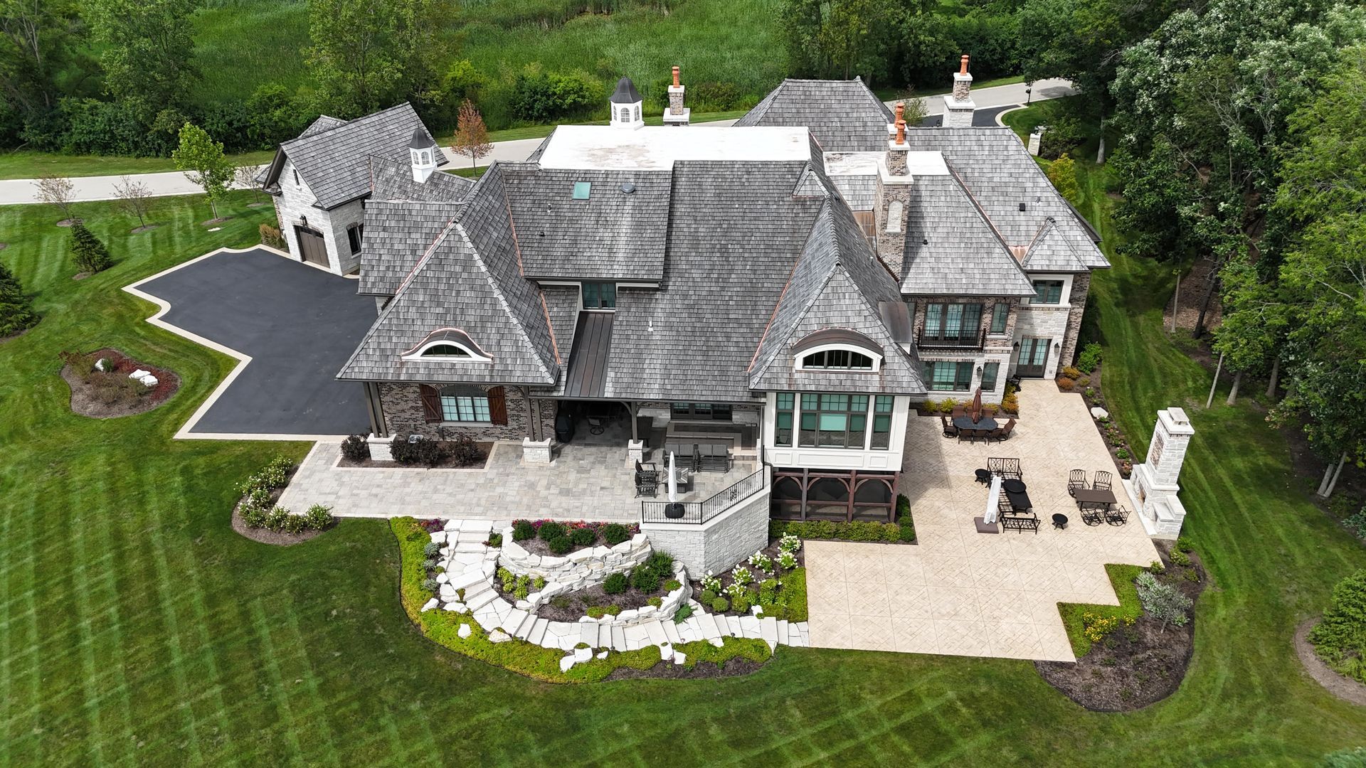 An aerial view of a large house surrounded by trees and grass.
