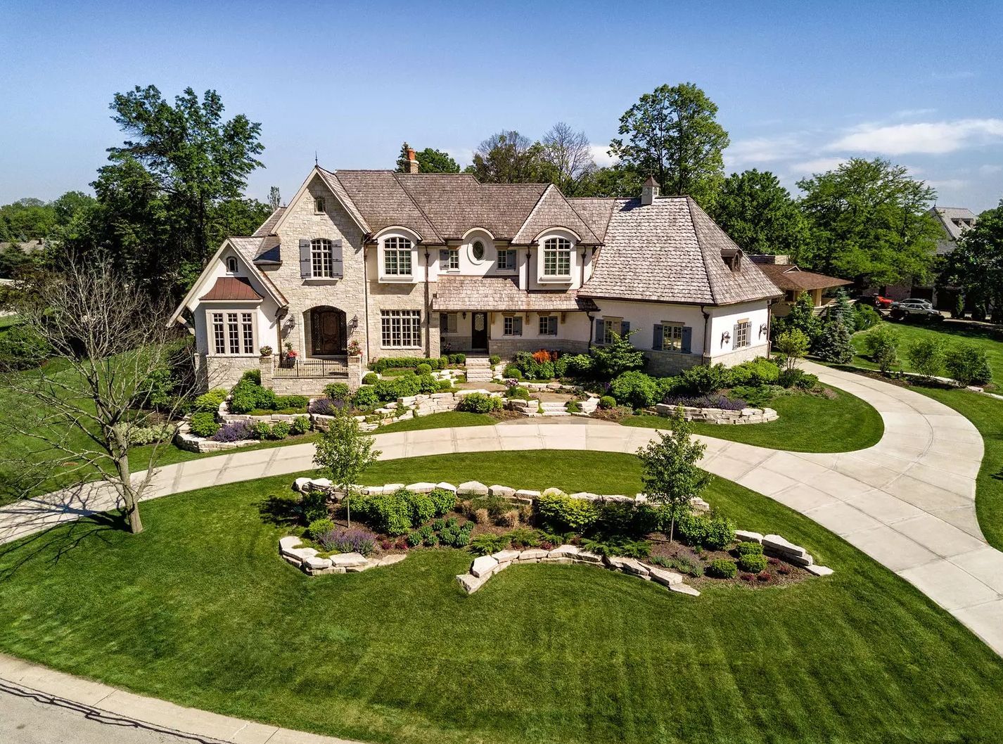 An aerial view of a large house with a large driveway leading to it.