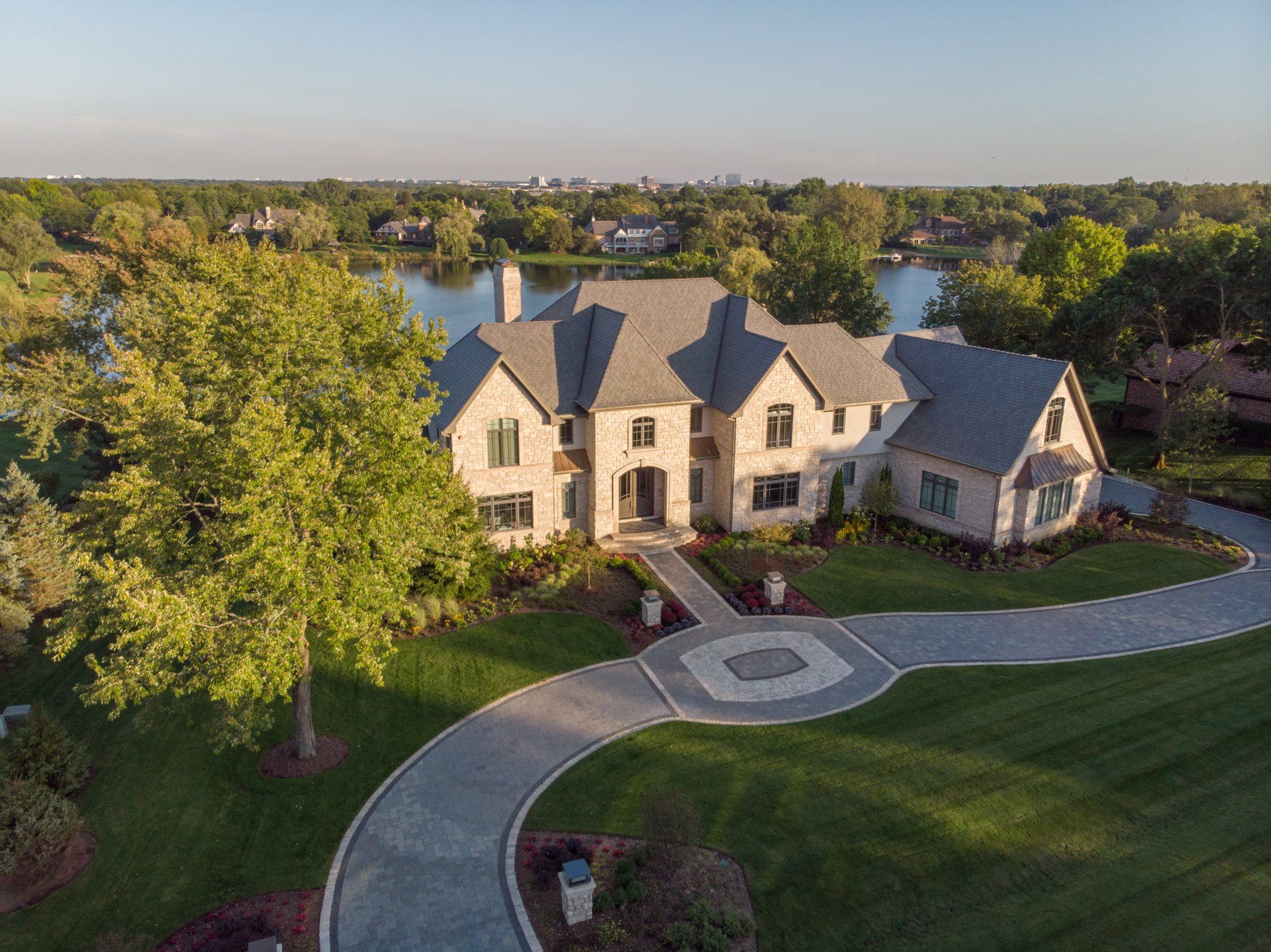 An aerial view of a large house with a lake in the background.
