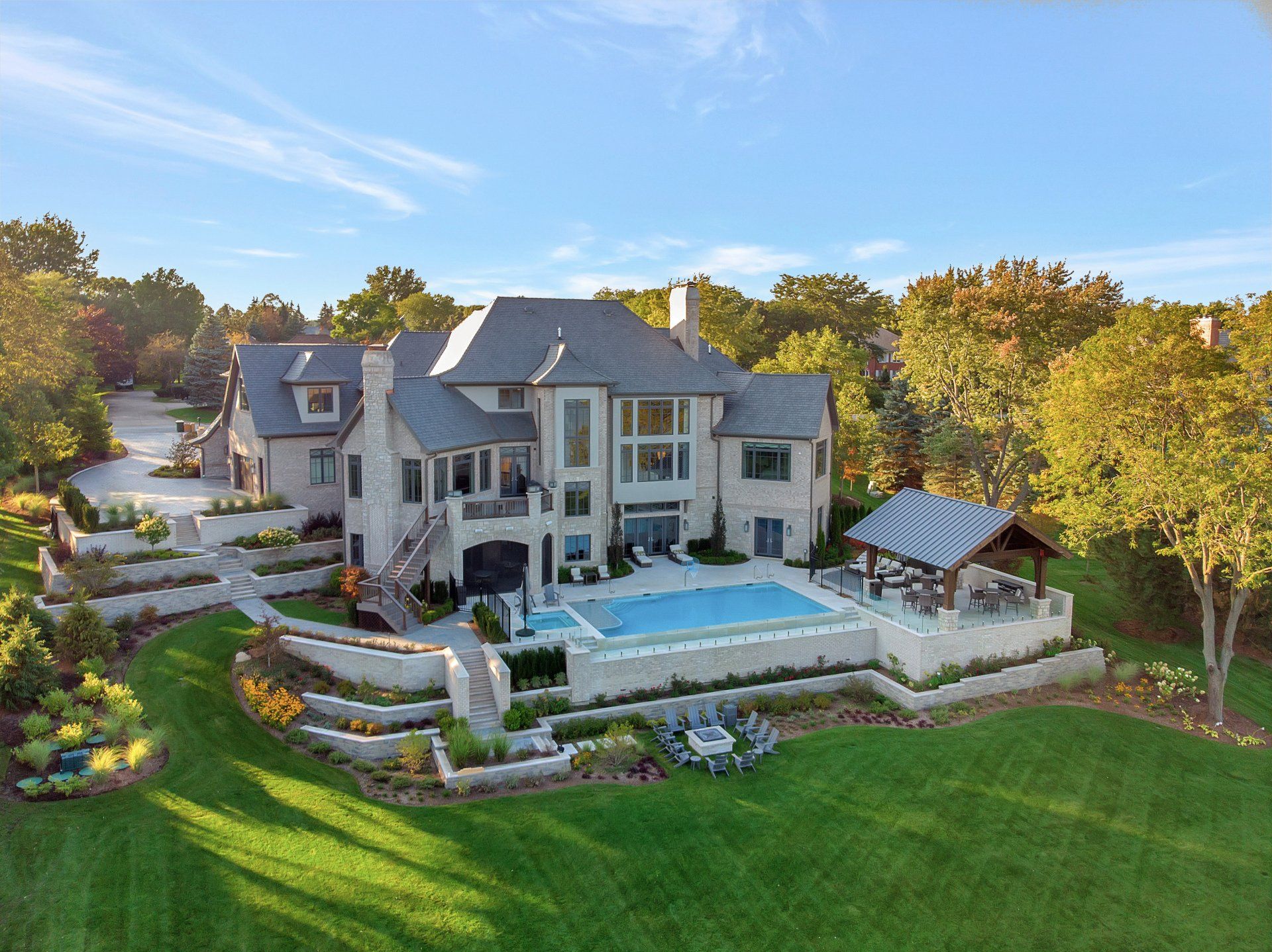 An aerial view of a large house with a swimming pool surrounded by trees.
