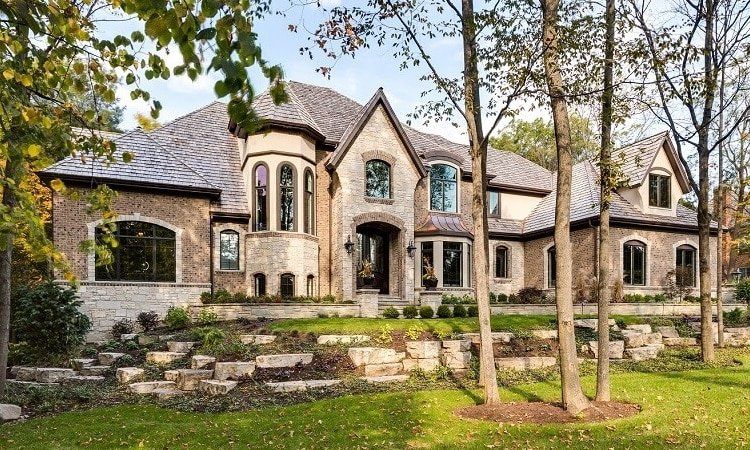 A large house with a lot of windows is surrounded by trees.