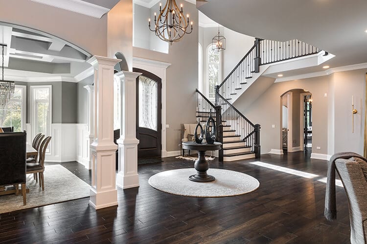 A large house with a staircase and a table in the middle of the room.